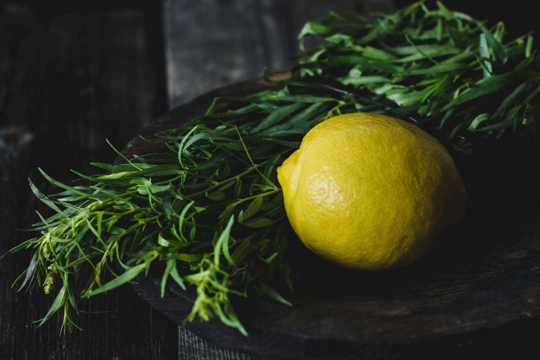 Close-up of a lemon and tarragon on black background.