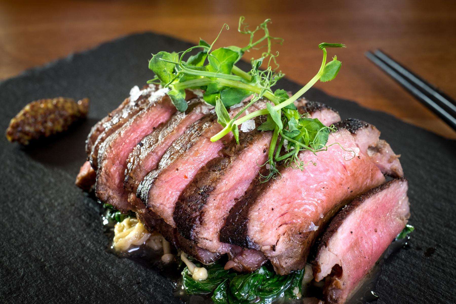 Sliced London broil on black plate.