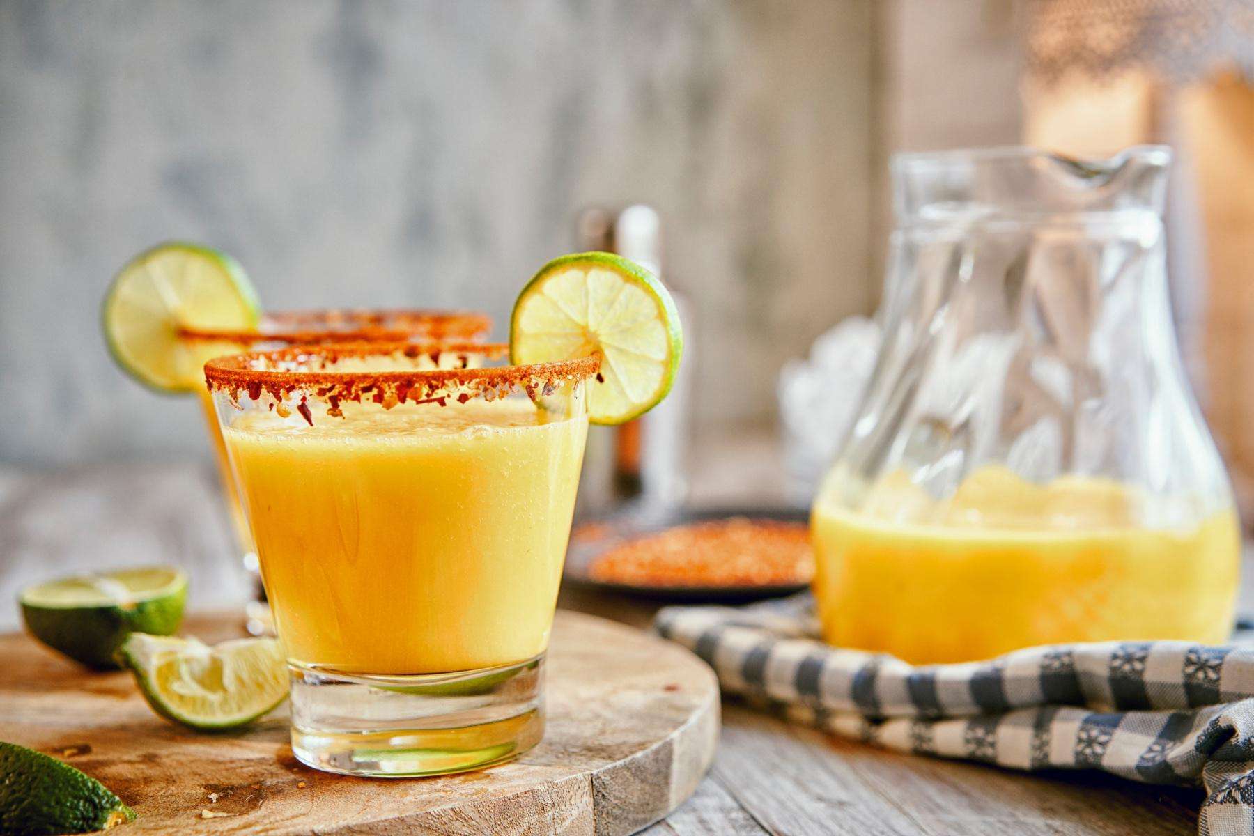 Mango margarita in glass with lime wedge.