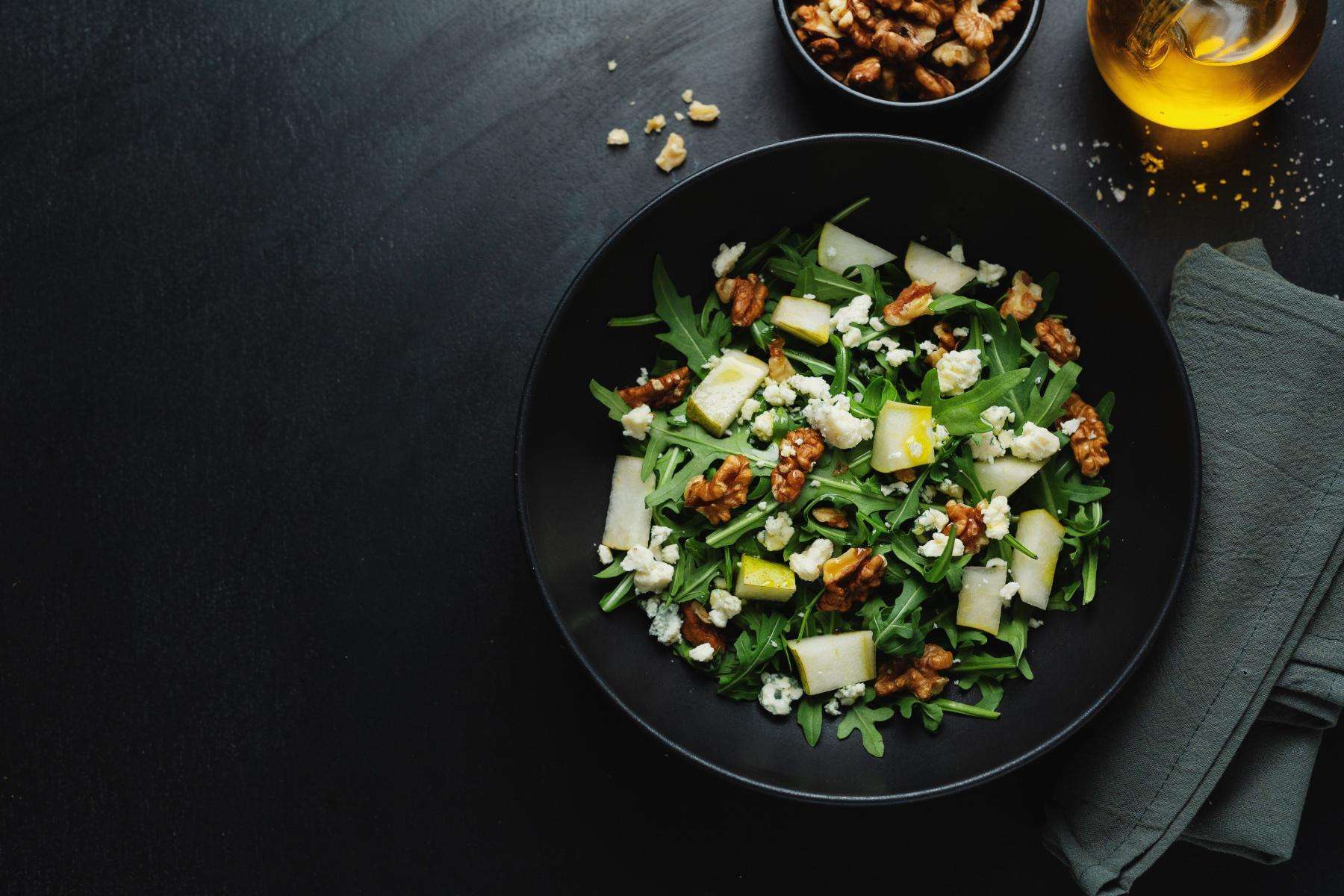 Overhead view of a bowl filled with an arugula and pear salad.