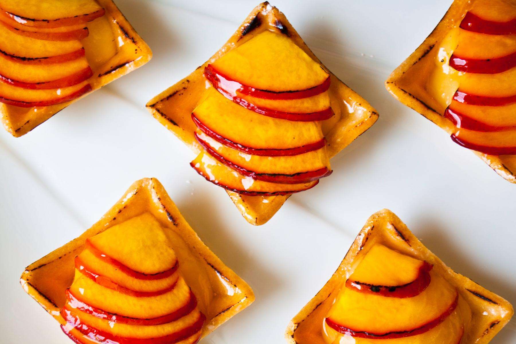 Overhead view of small peach tarts on white background.