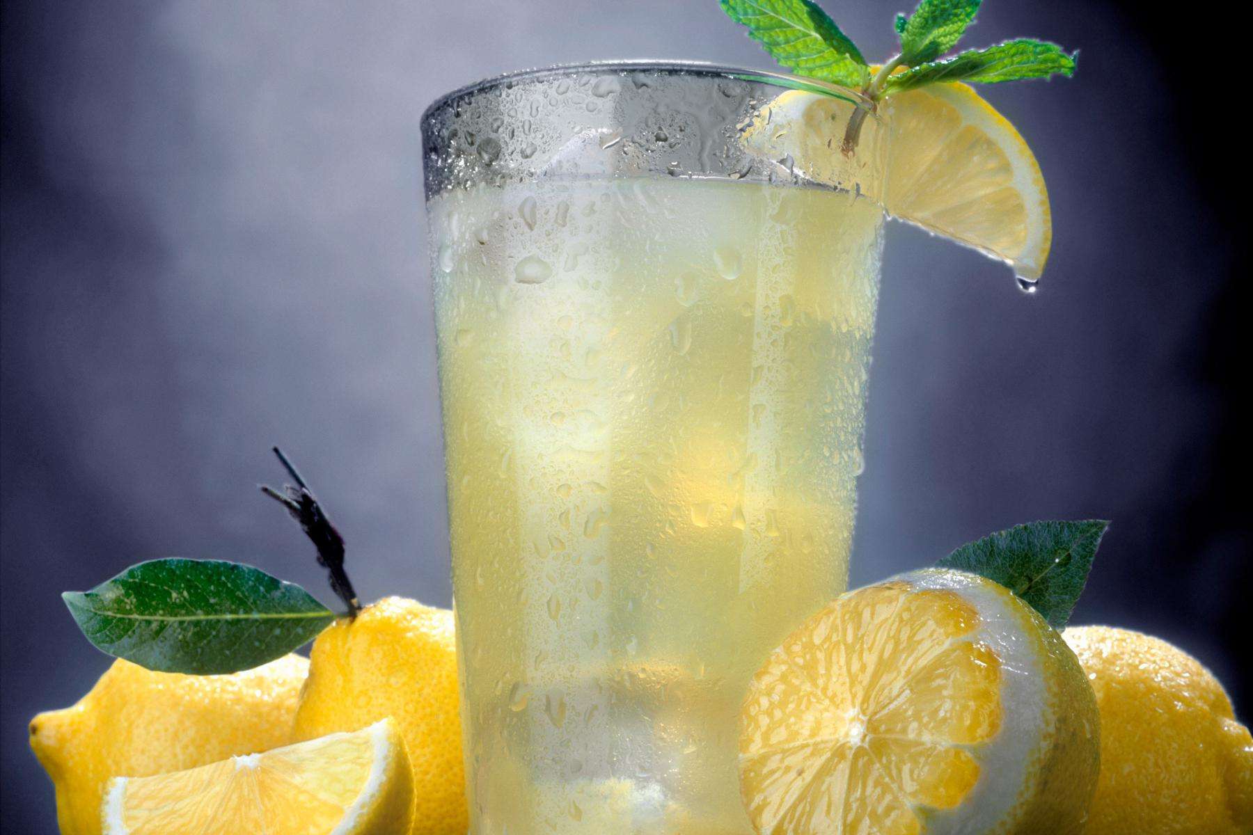 Close-up of glass of lemonade with cut lemons surrounding it.