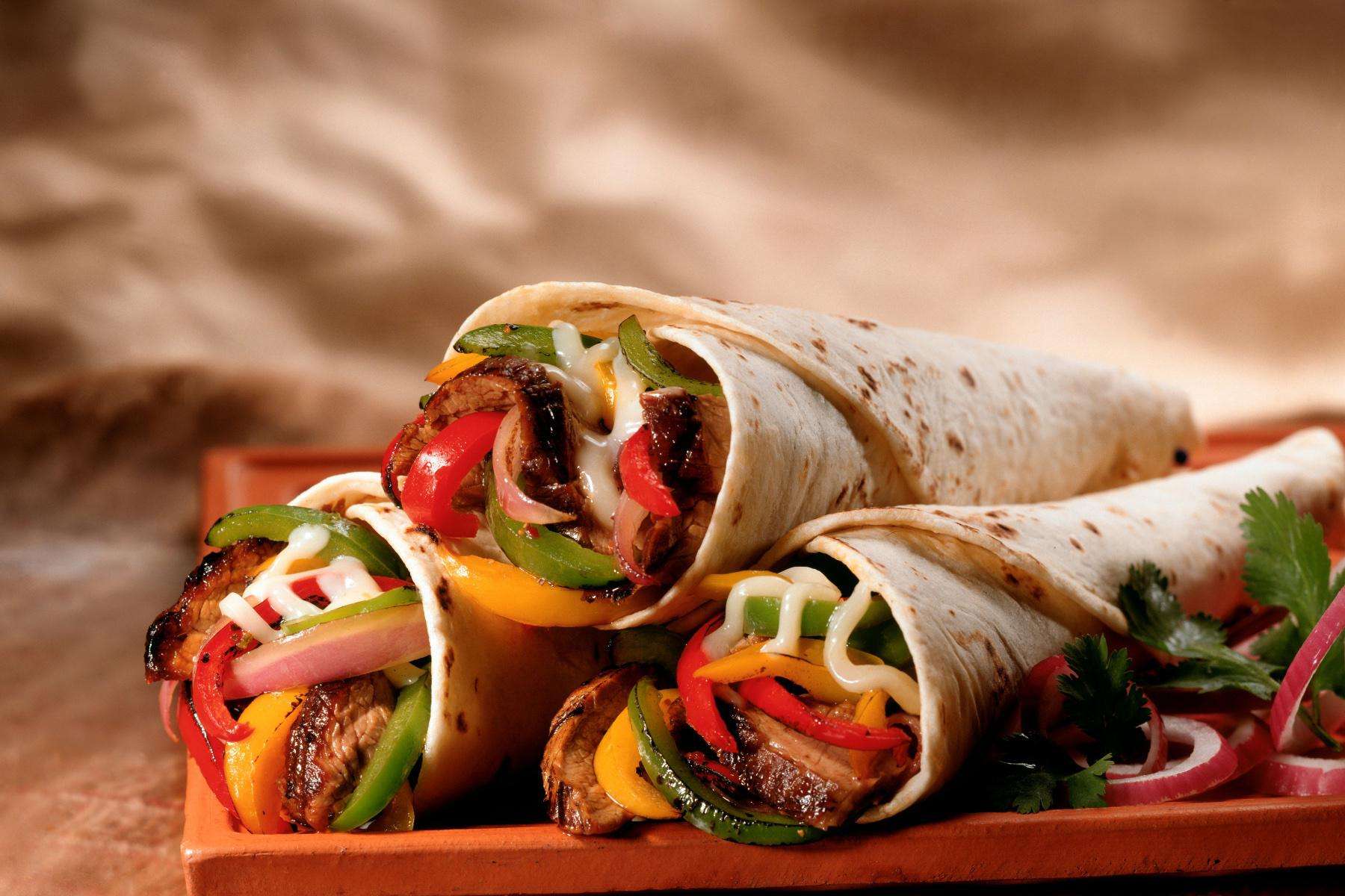 Close-up of steak fajitas on red plate.