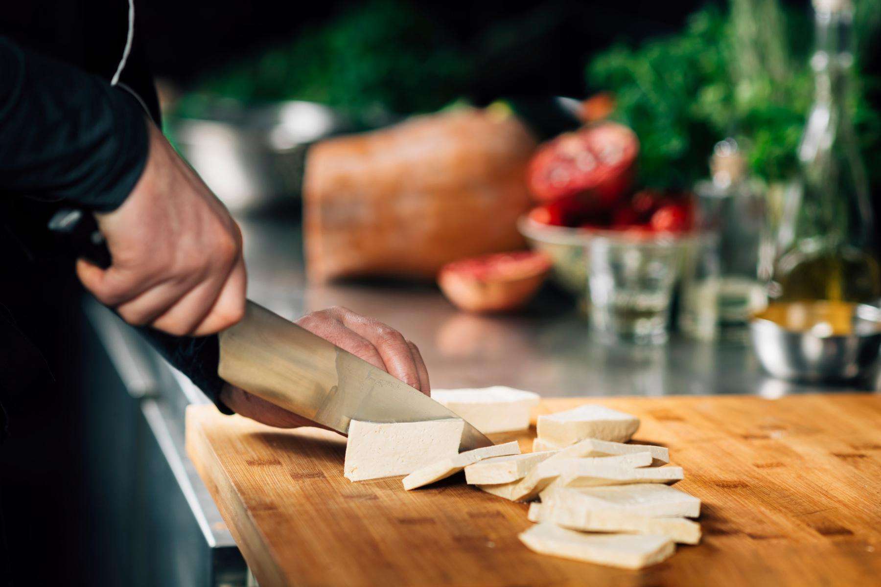 Chopping tofu into slices.