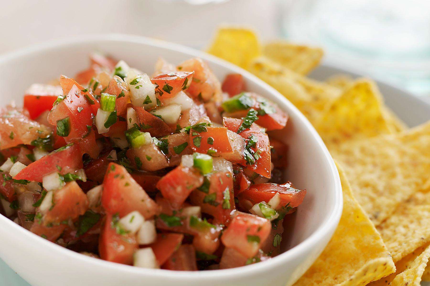 Bowl of pico de Gallo with chips on the side.