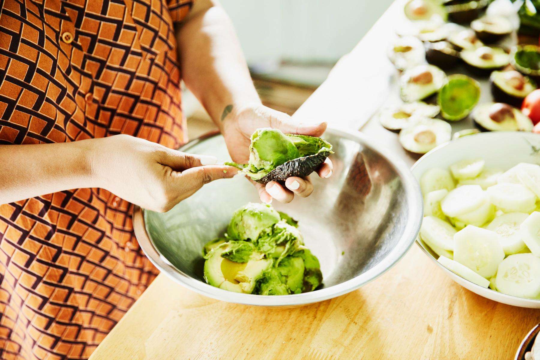 Close-up of woman making guacamole in silver bowl.