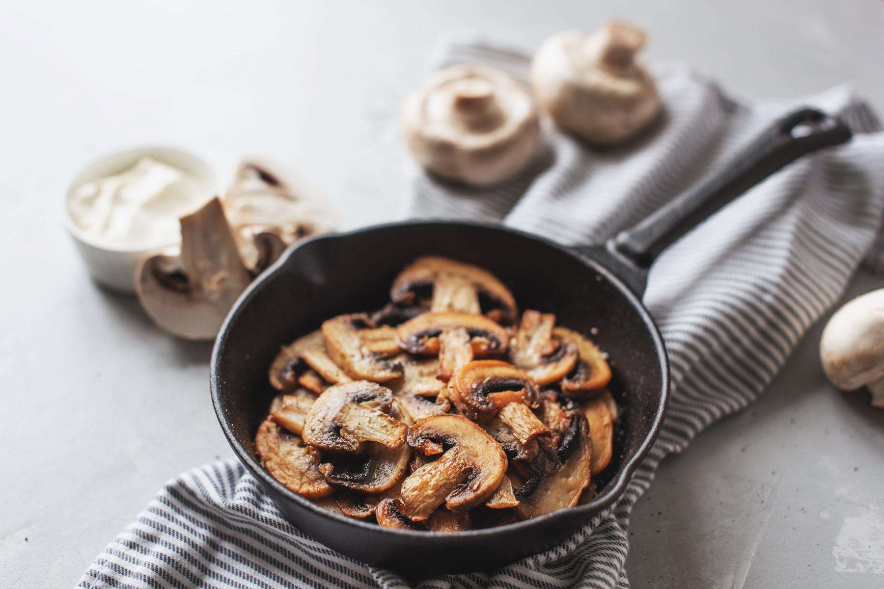 Overhead view of frying pan with chopped mushrooms.