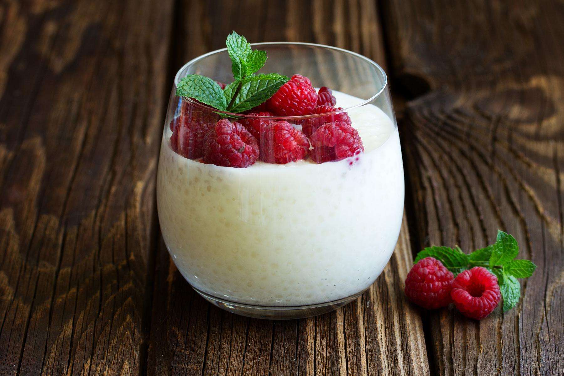 A glass of tapioca pudding with raspberries.