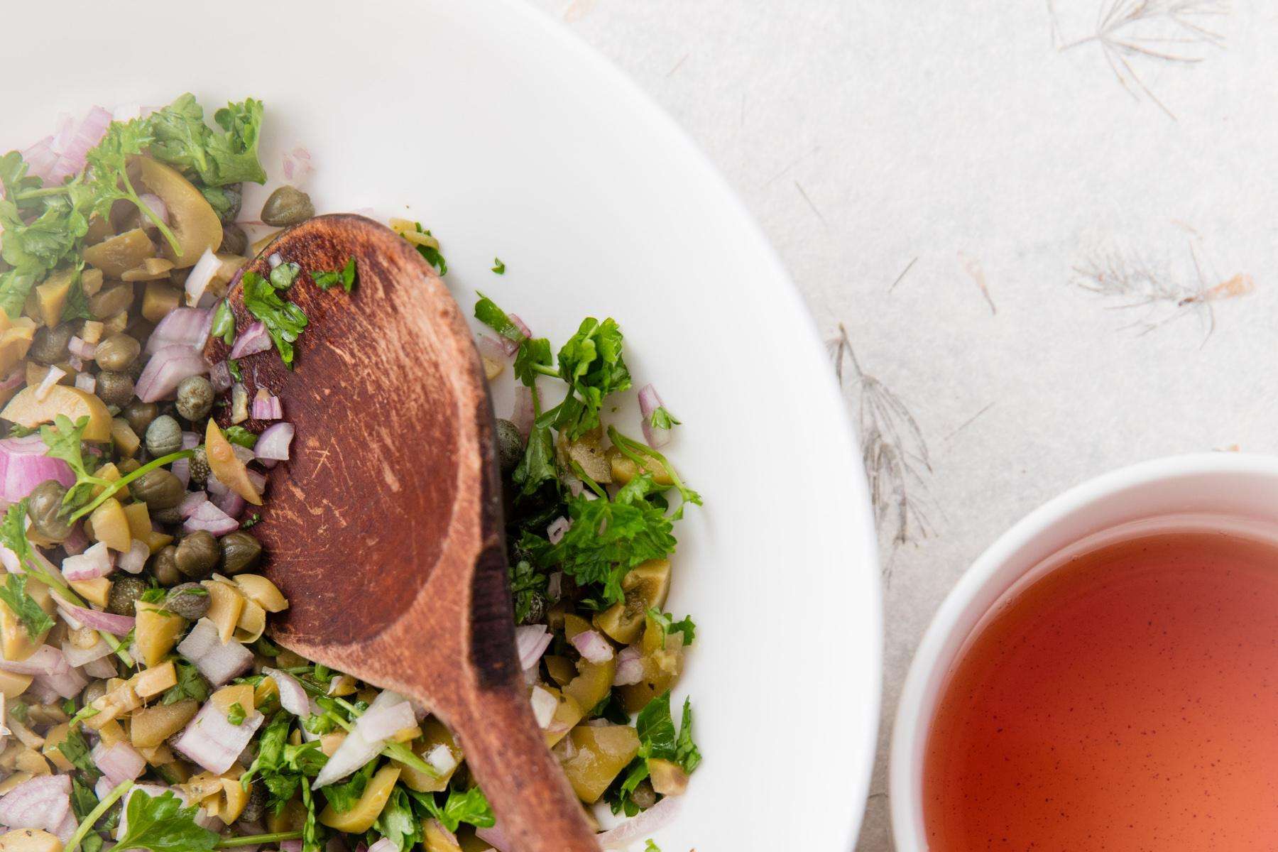 Bowl of red wine vinaigrette next to salad.