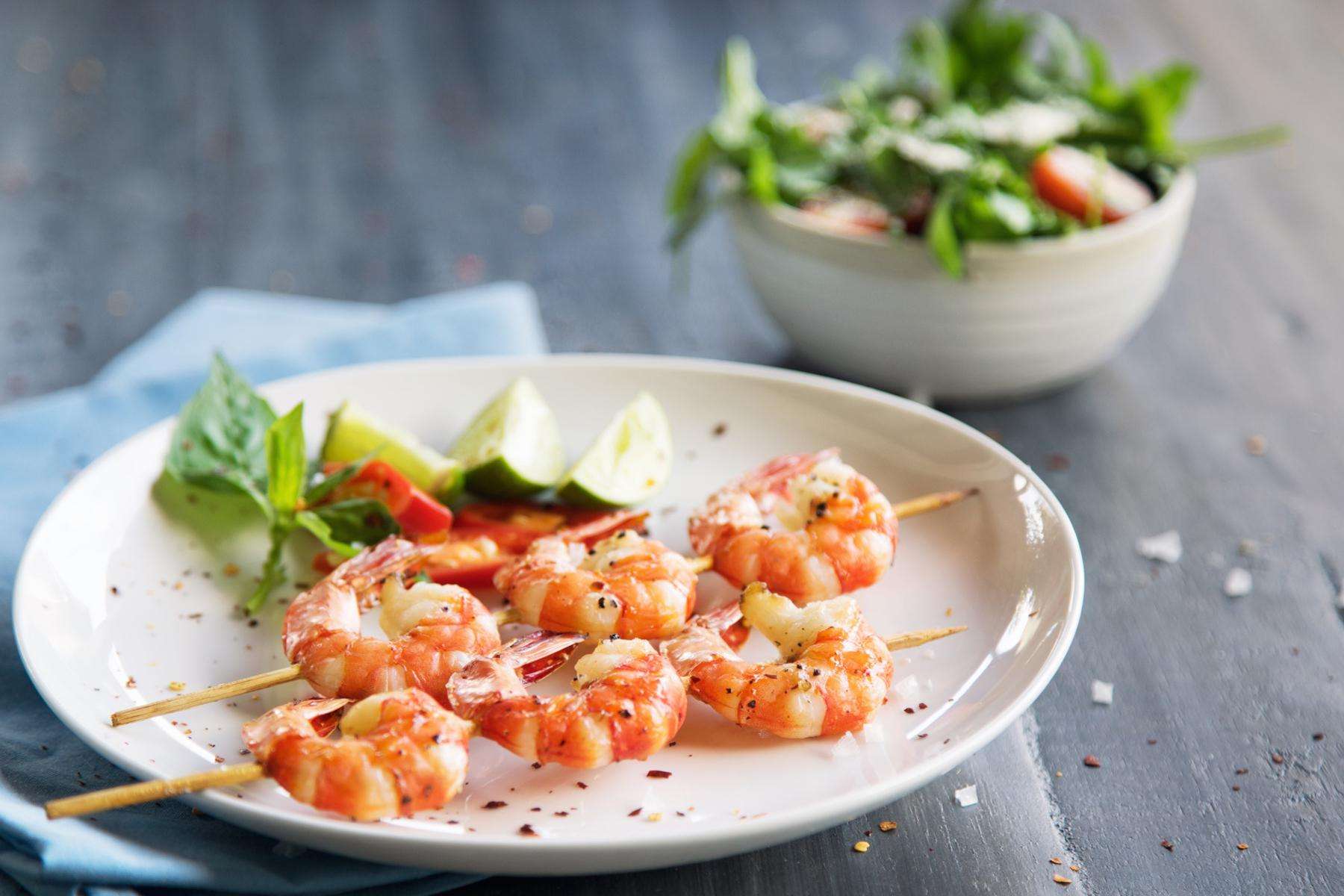 Plate of grilled shrimp on skewer.
