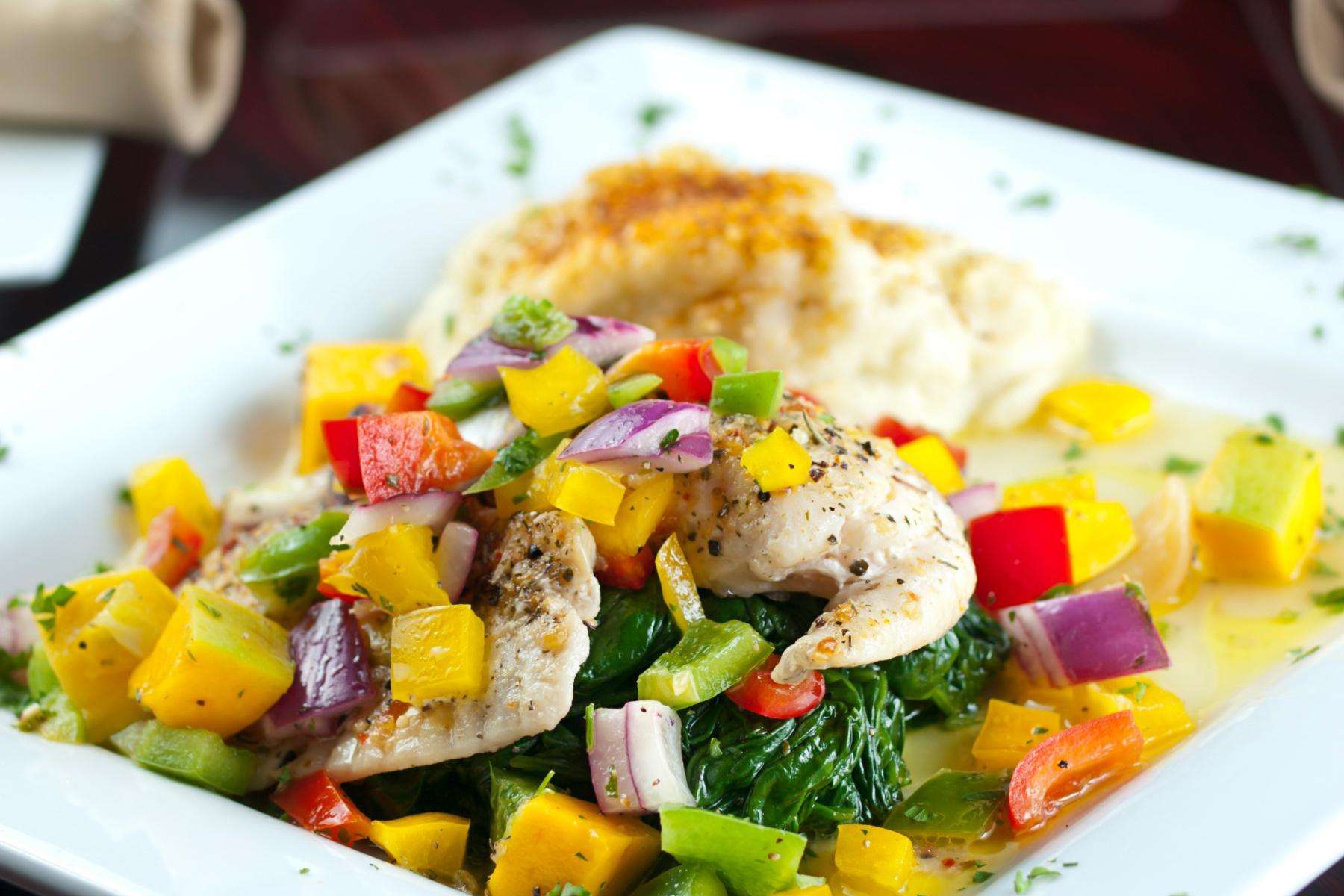 Close-up of tilapia with brightly color salsa on top.