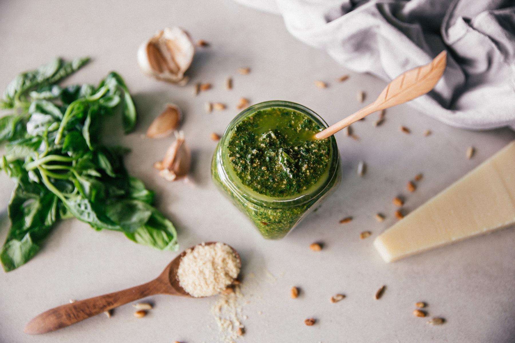 Overhead view of a jar of pesto surrounded by ingredients.