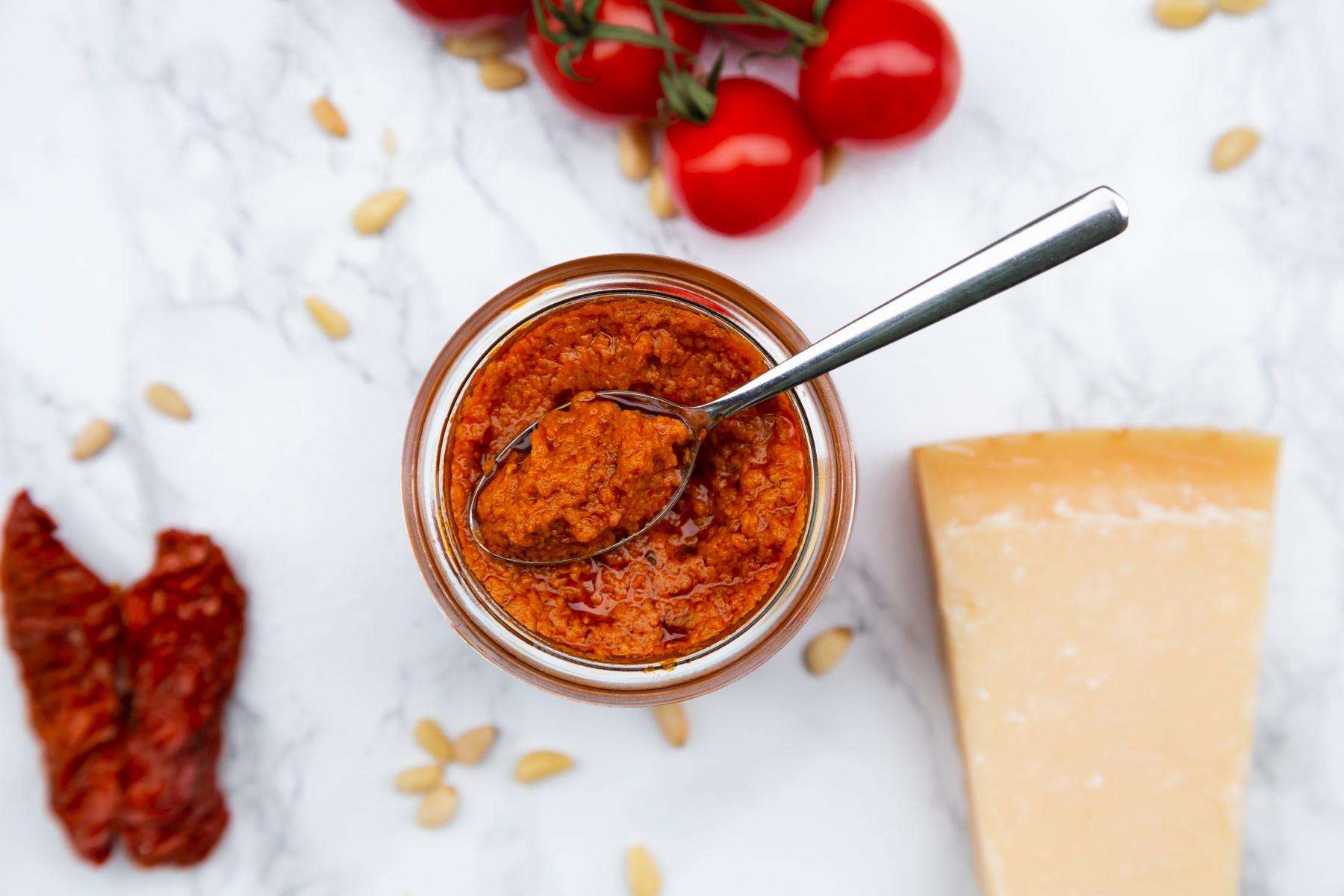 Overhead view of red pepper pesto in glass jar.