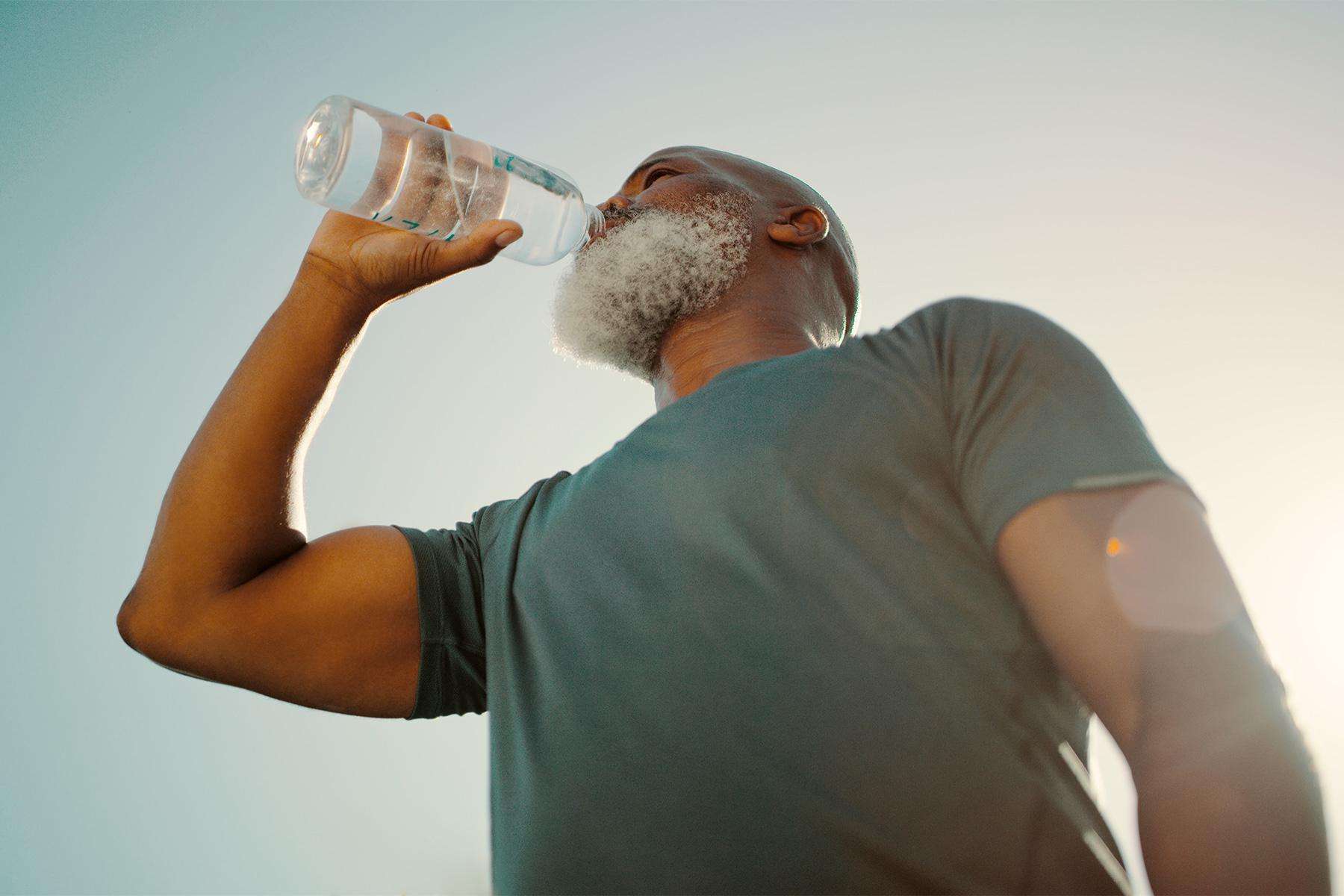 Man drinking from a water bottle outside.