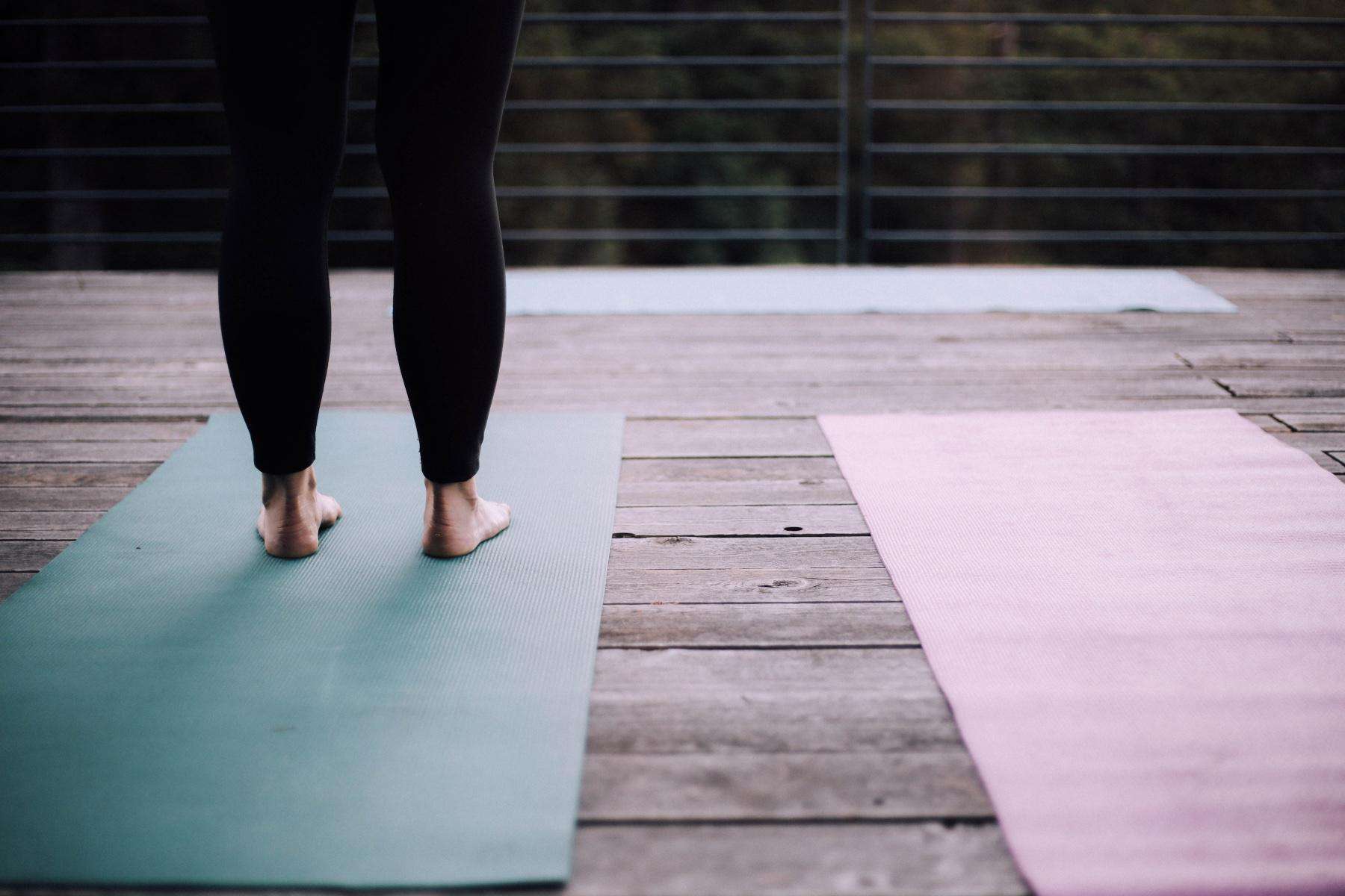 woman's feet standing on yoga mat on deck outside