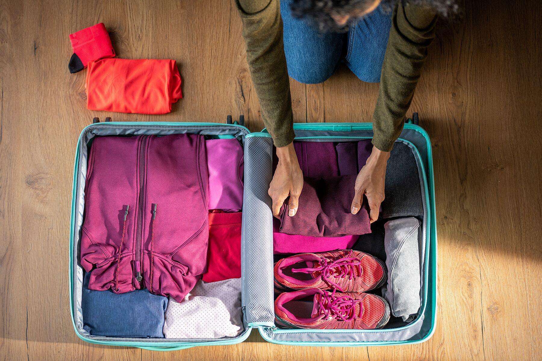 Woman packing her suitcase on the floor.