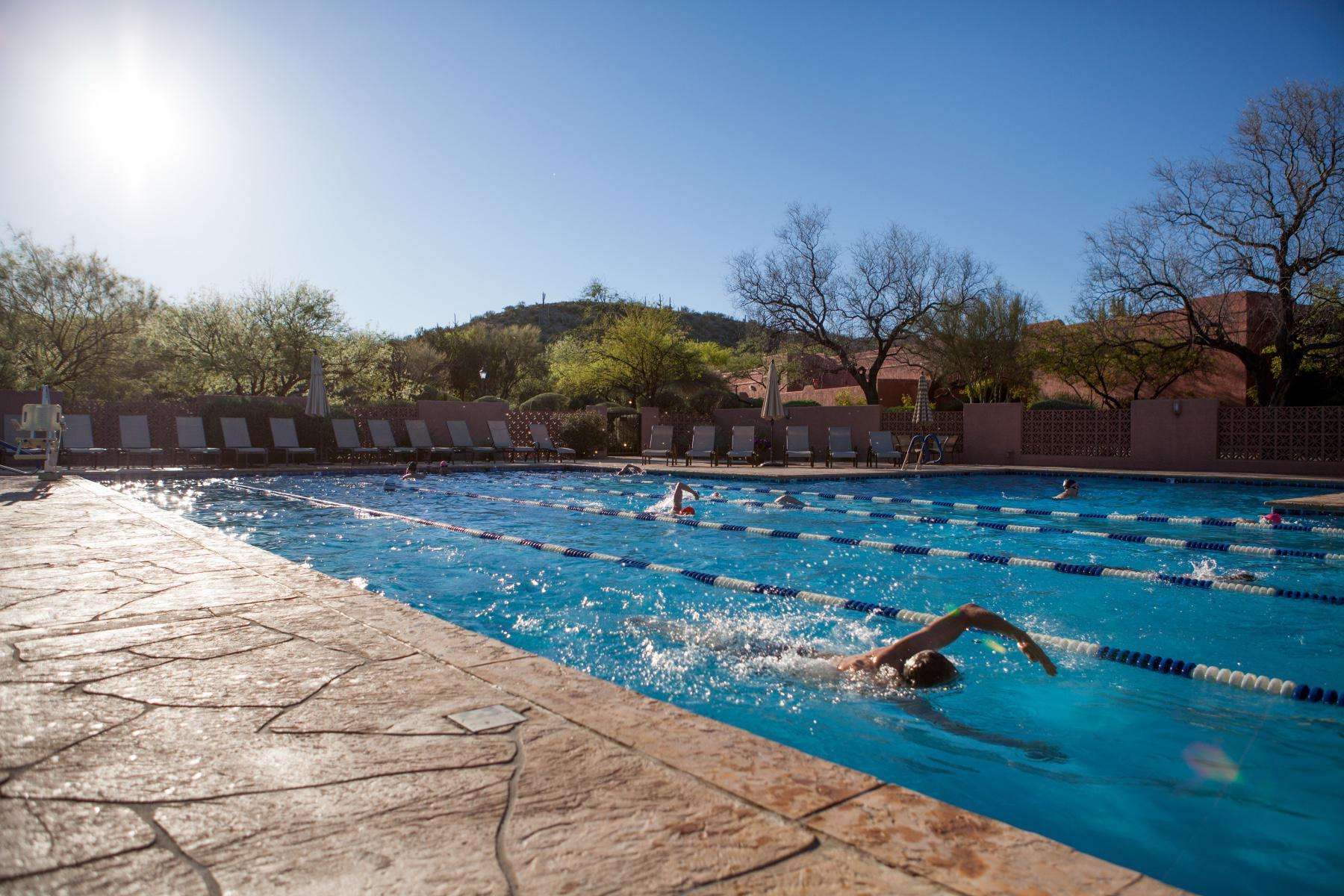wide angle shot of many swimmers doing laps in outdoor pool
