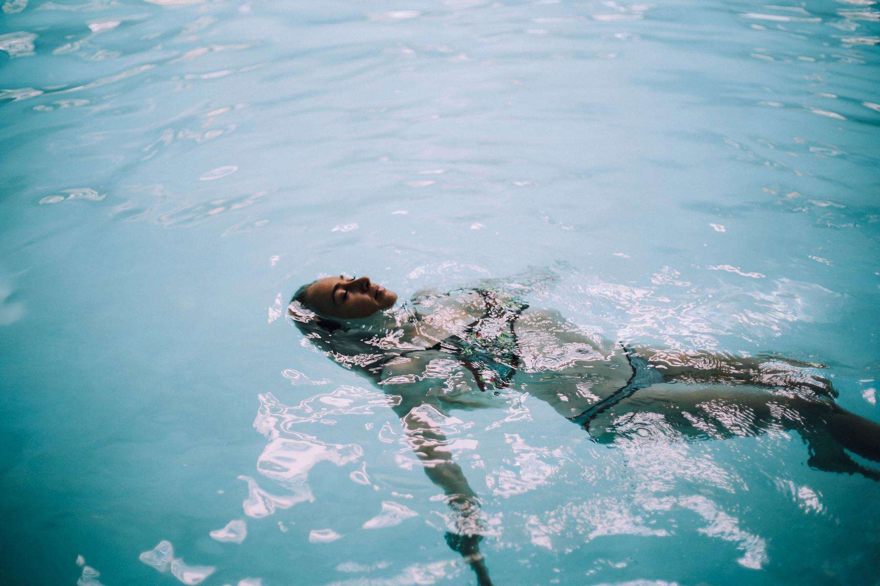 young woman floating on her back in pool