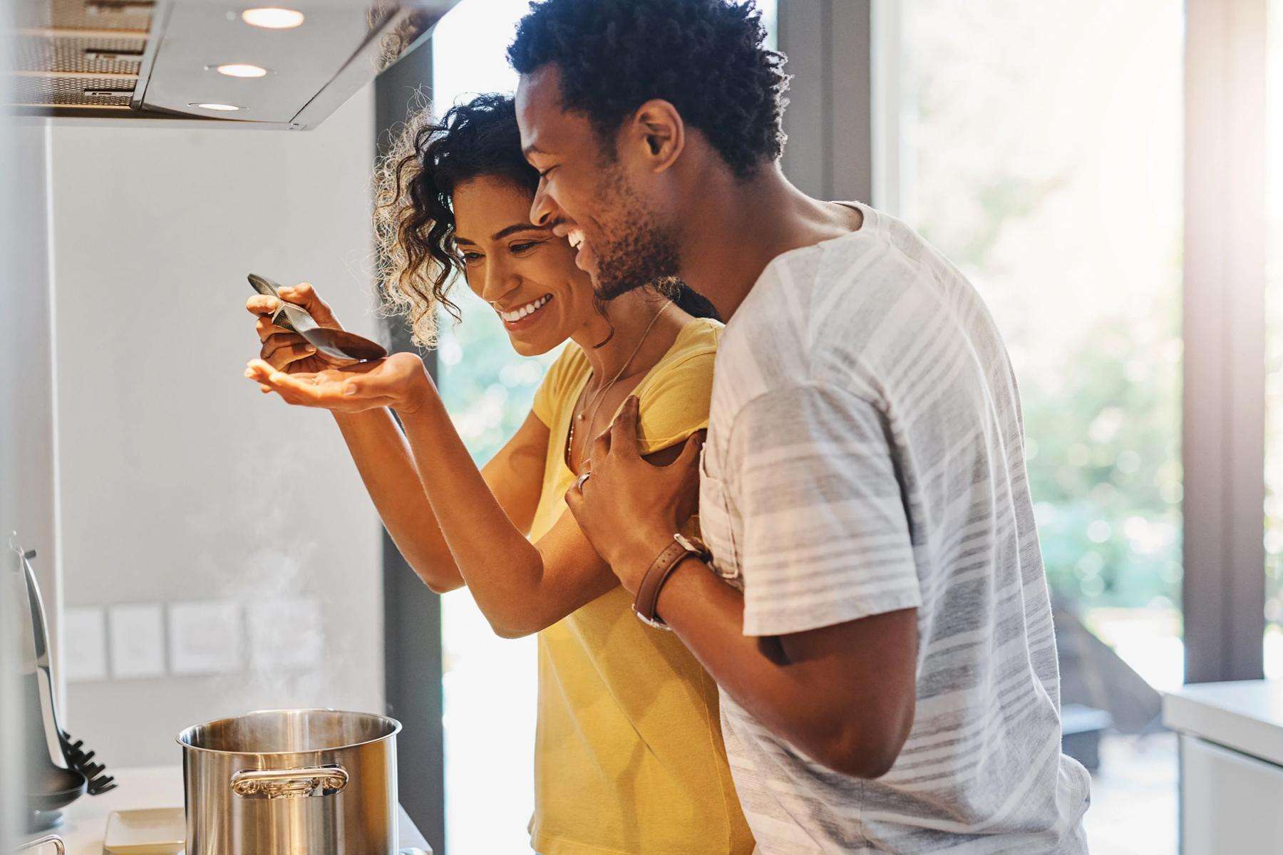 man and woman cooking together and smiling