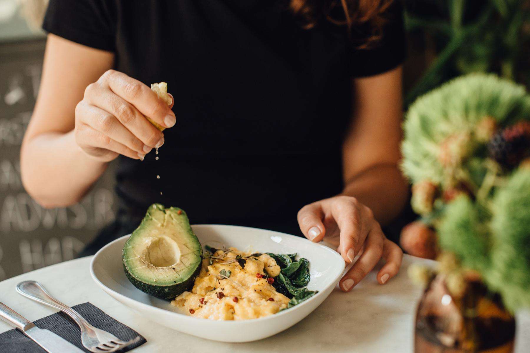 Woman squeezing lemon onto avocado.