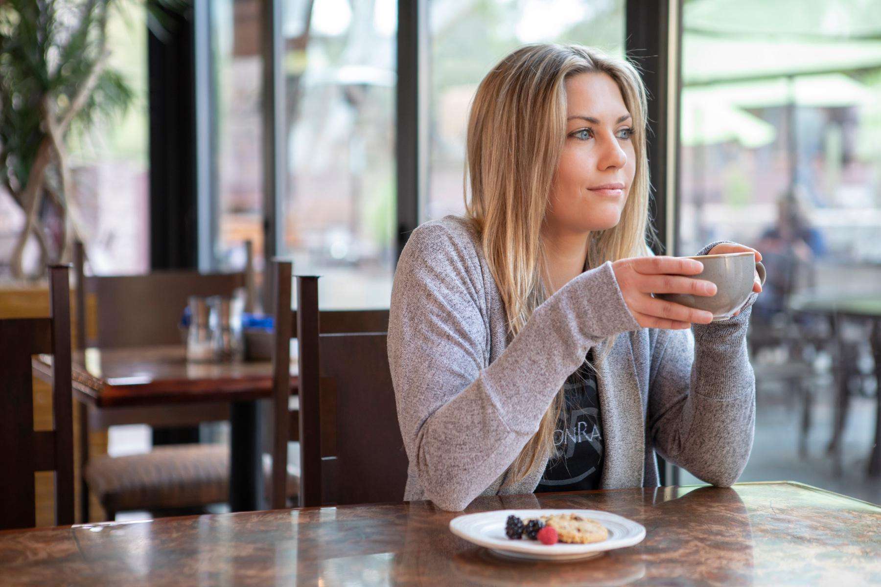 woman holding coffee cup and looking out window