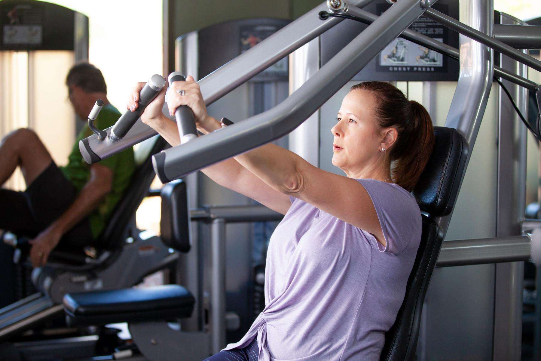woman using chest press machine in gym