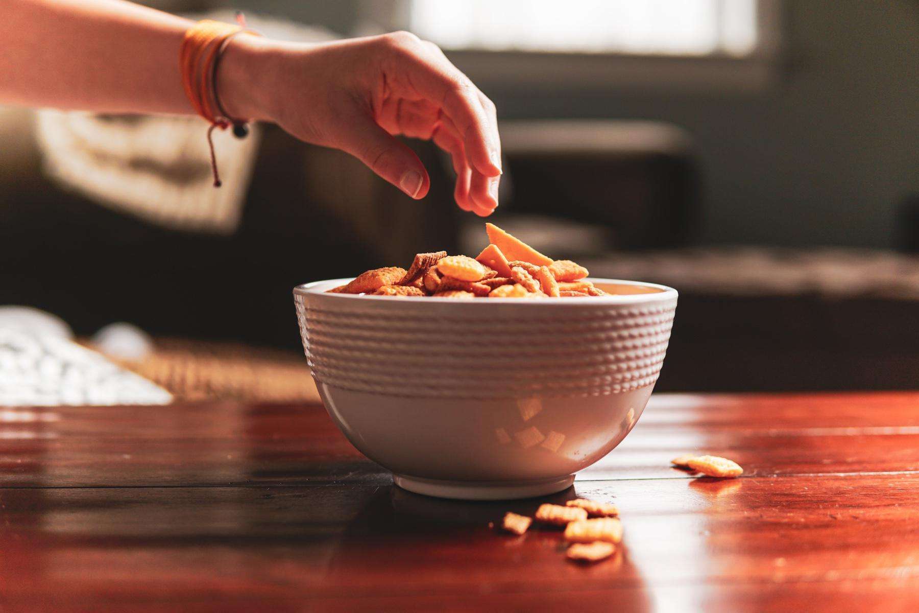 Hand reaching for bowl of snacks.