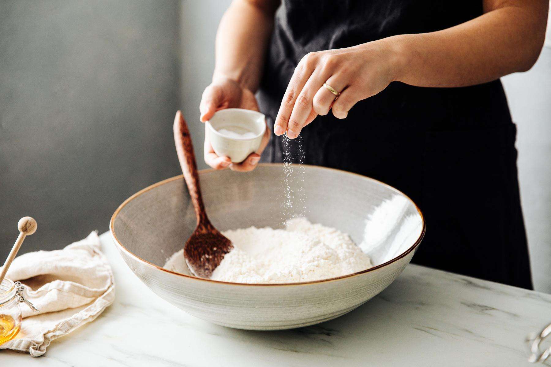 woman salting bowl of flour