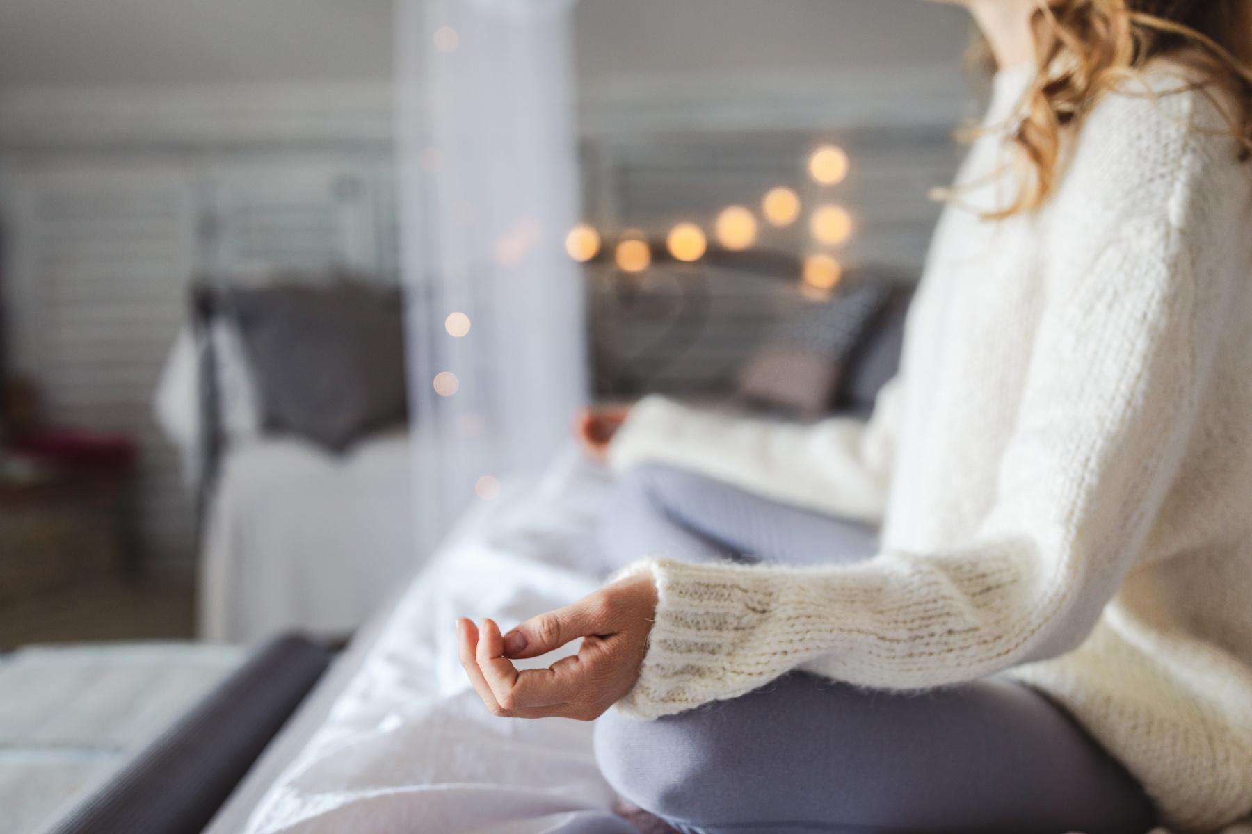 Woman meditating on her bed.