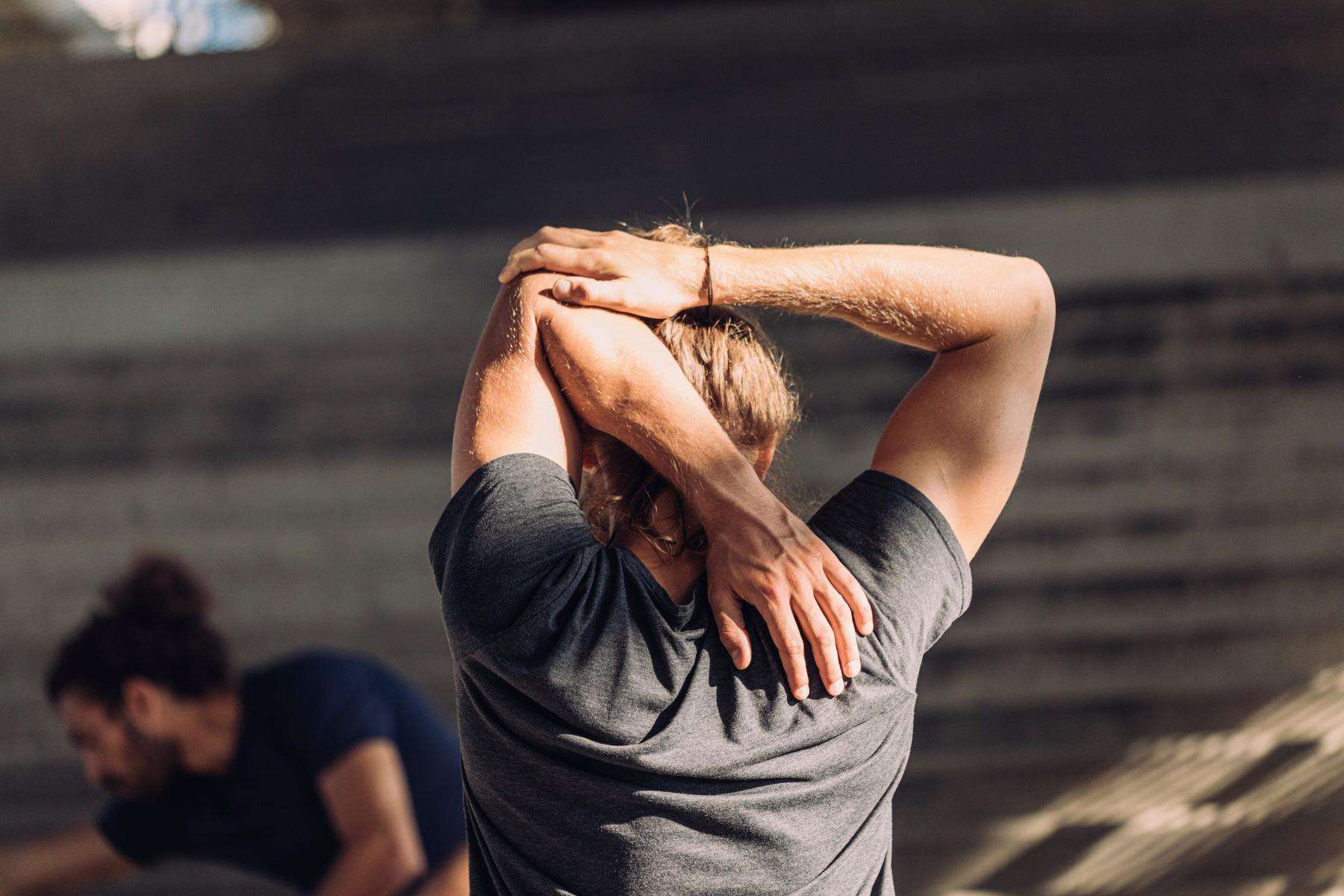 close-up of man's back as he stretches his arms behind his head