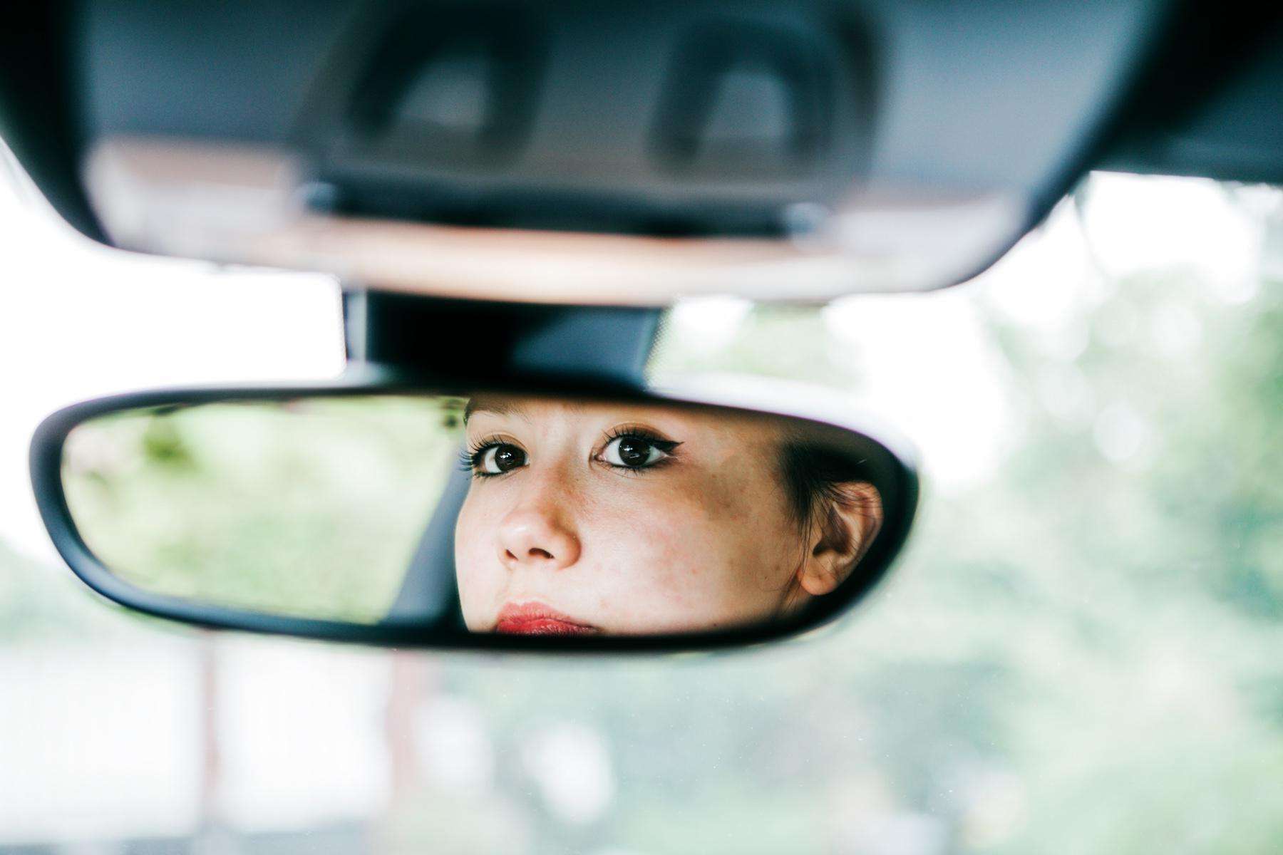 Woman looking in rear view mirror.