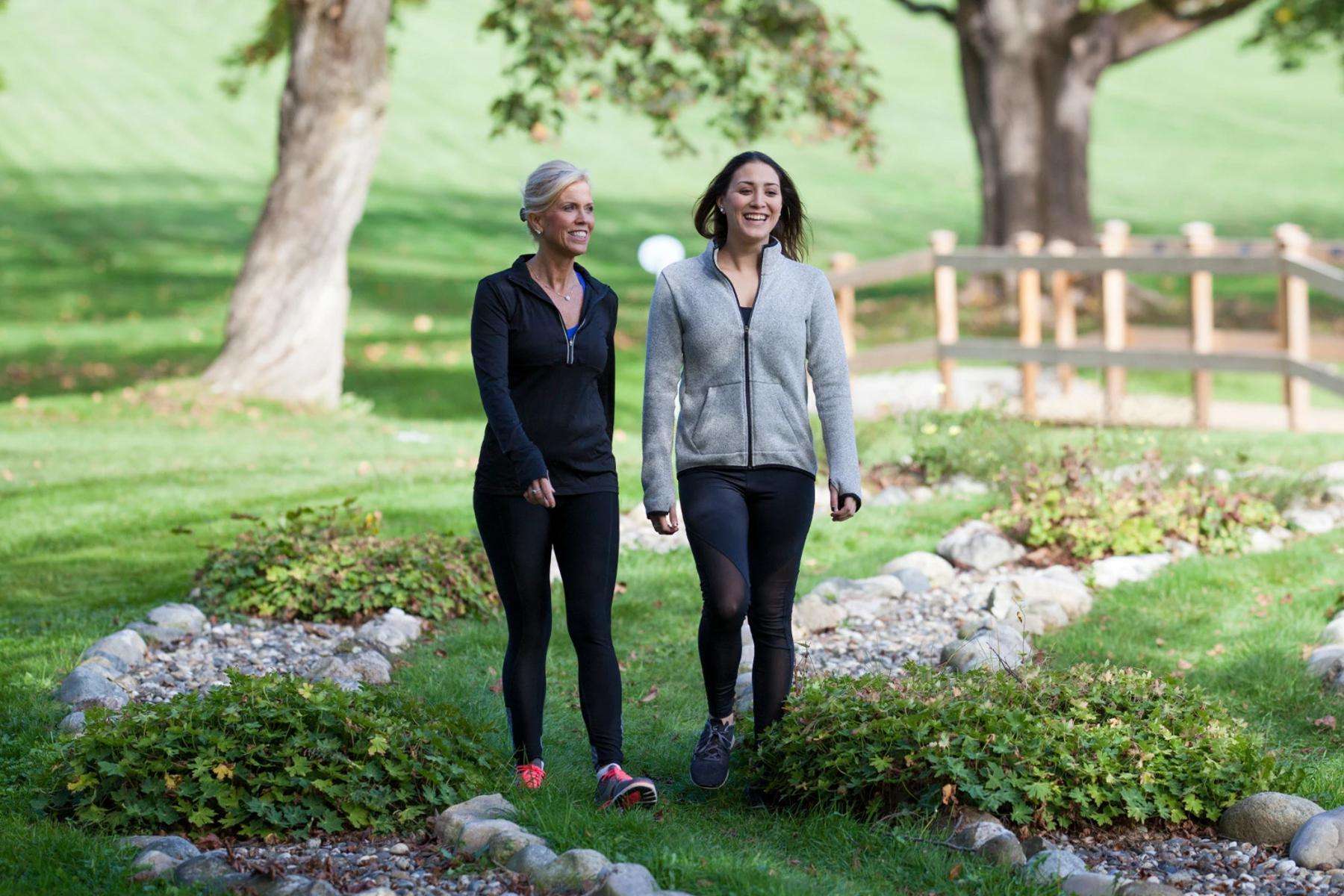mother and daughter smiling while walking through labyrinth path with rock edges on grass