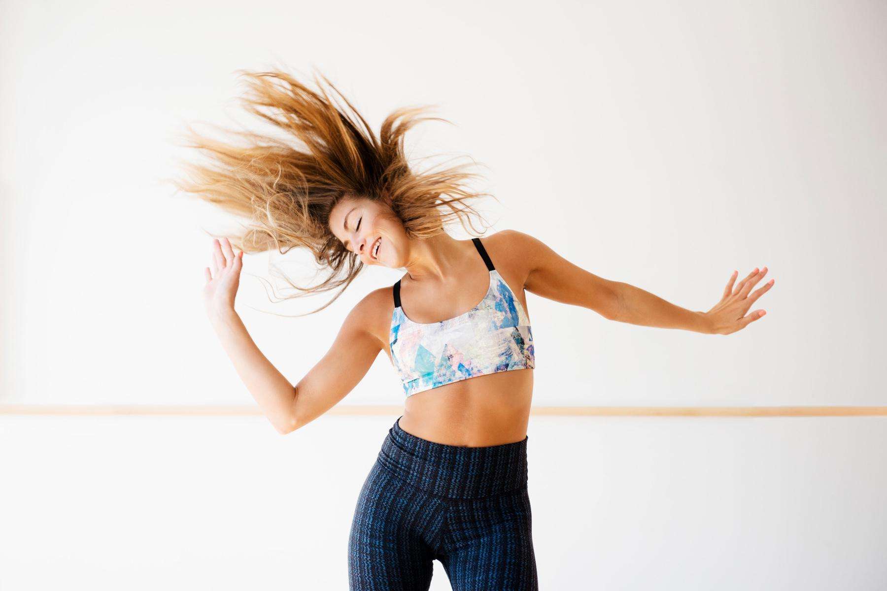 woman mid-dance move throwing hands to the side and flipping hair