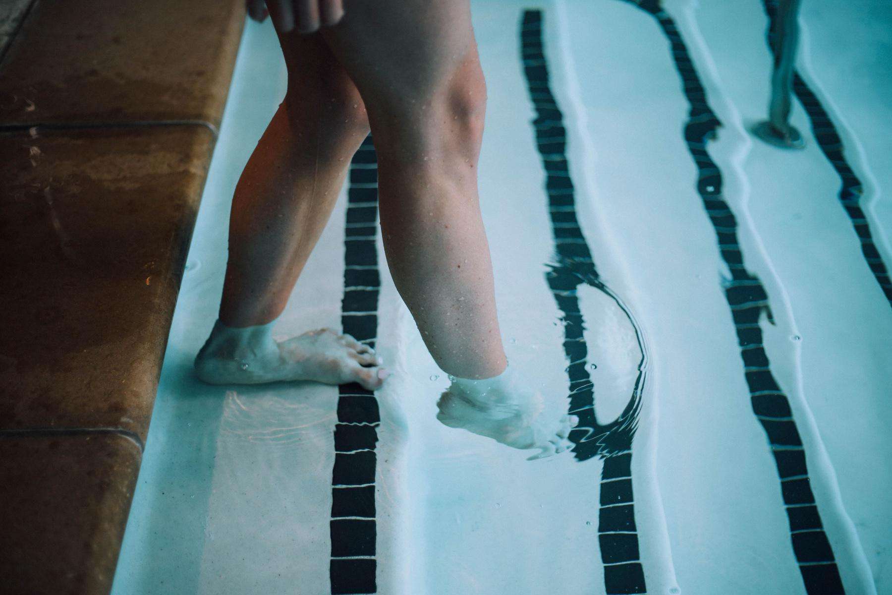 close-up of a woman's feet stepping down into pool