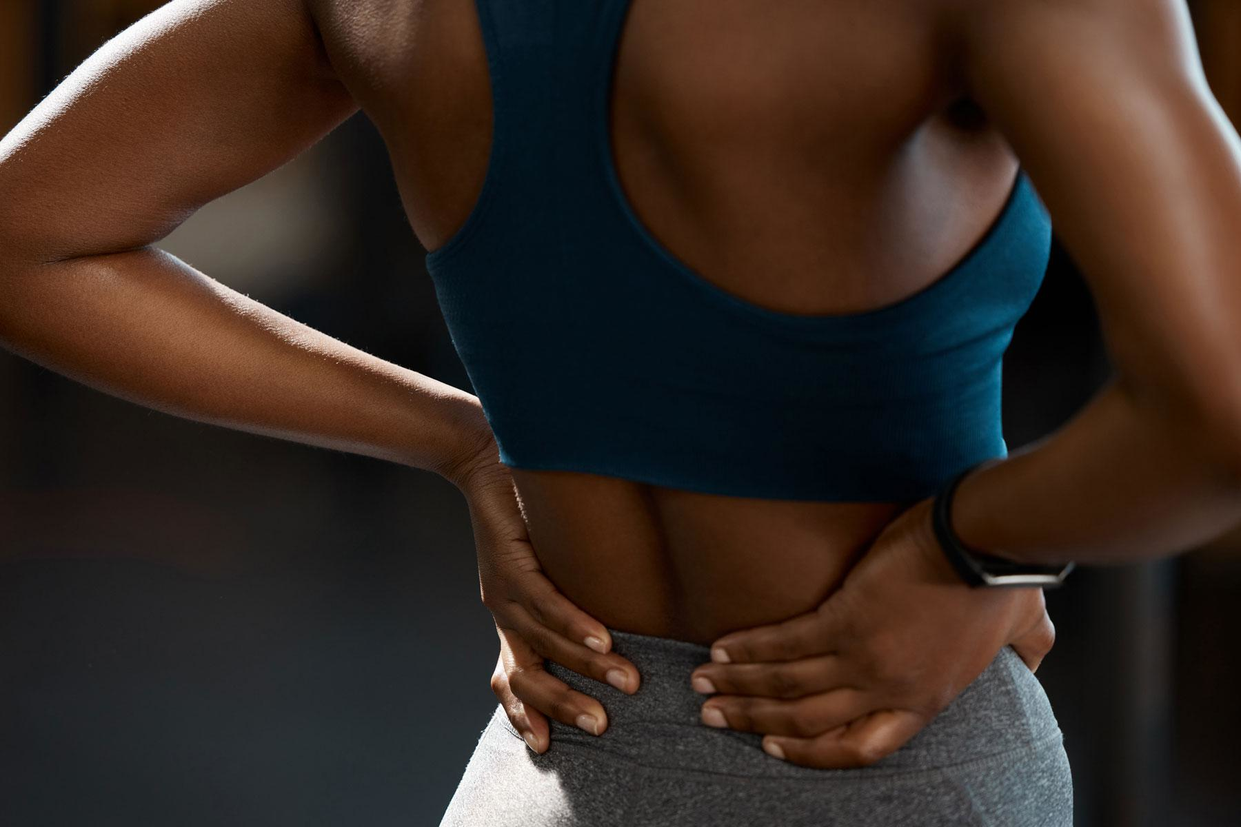 Close-up of woman holding lower back.