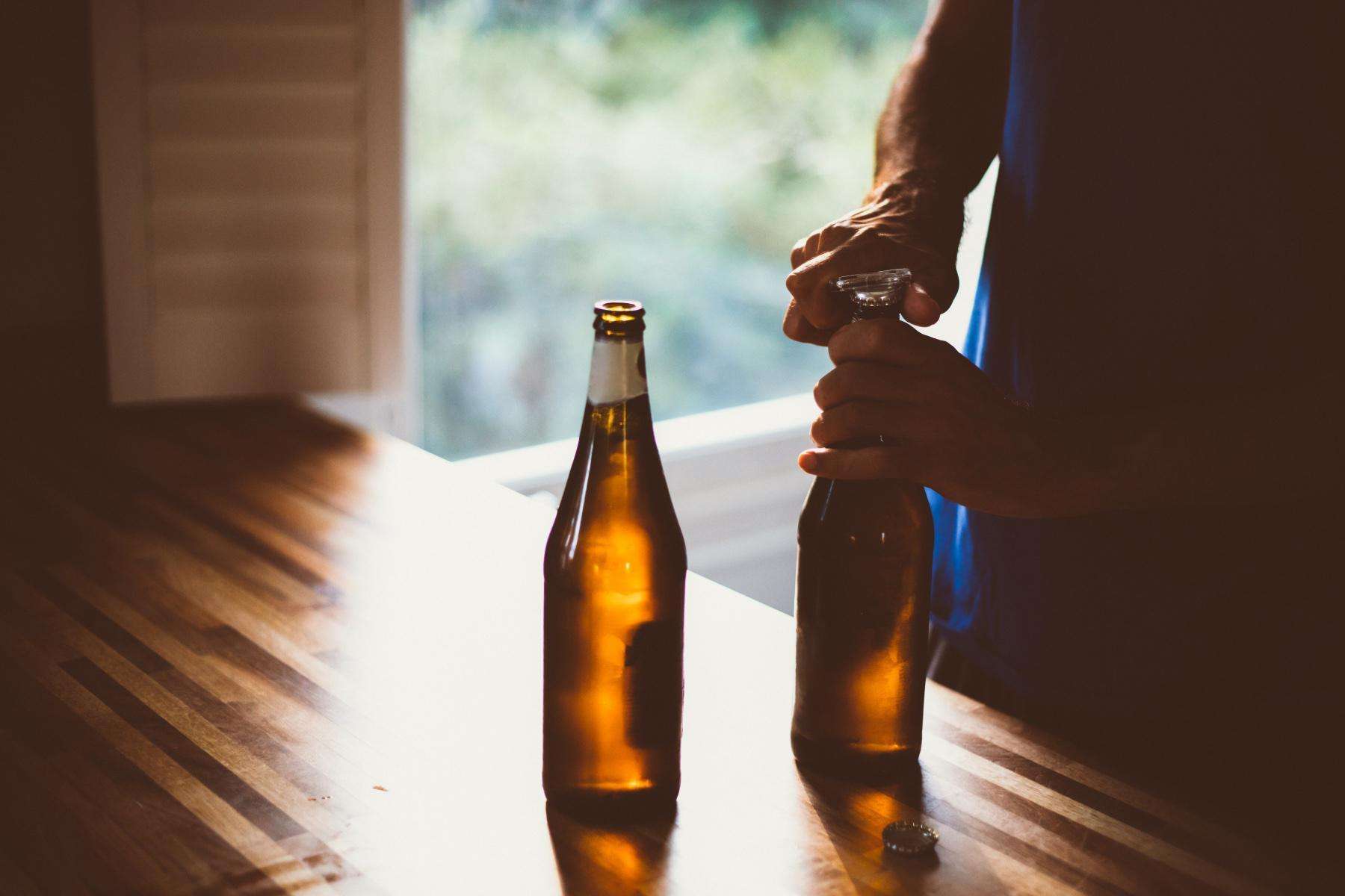 close-up of man opening two bottles of beer