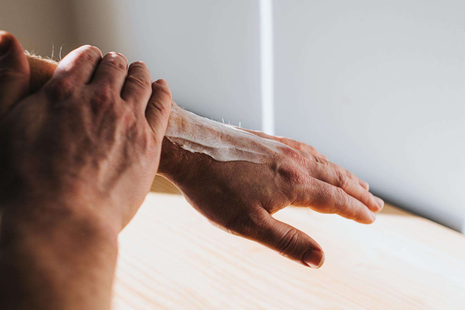 A man rubbing shea butter into his arm.