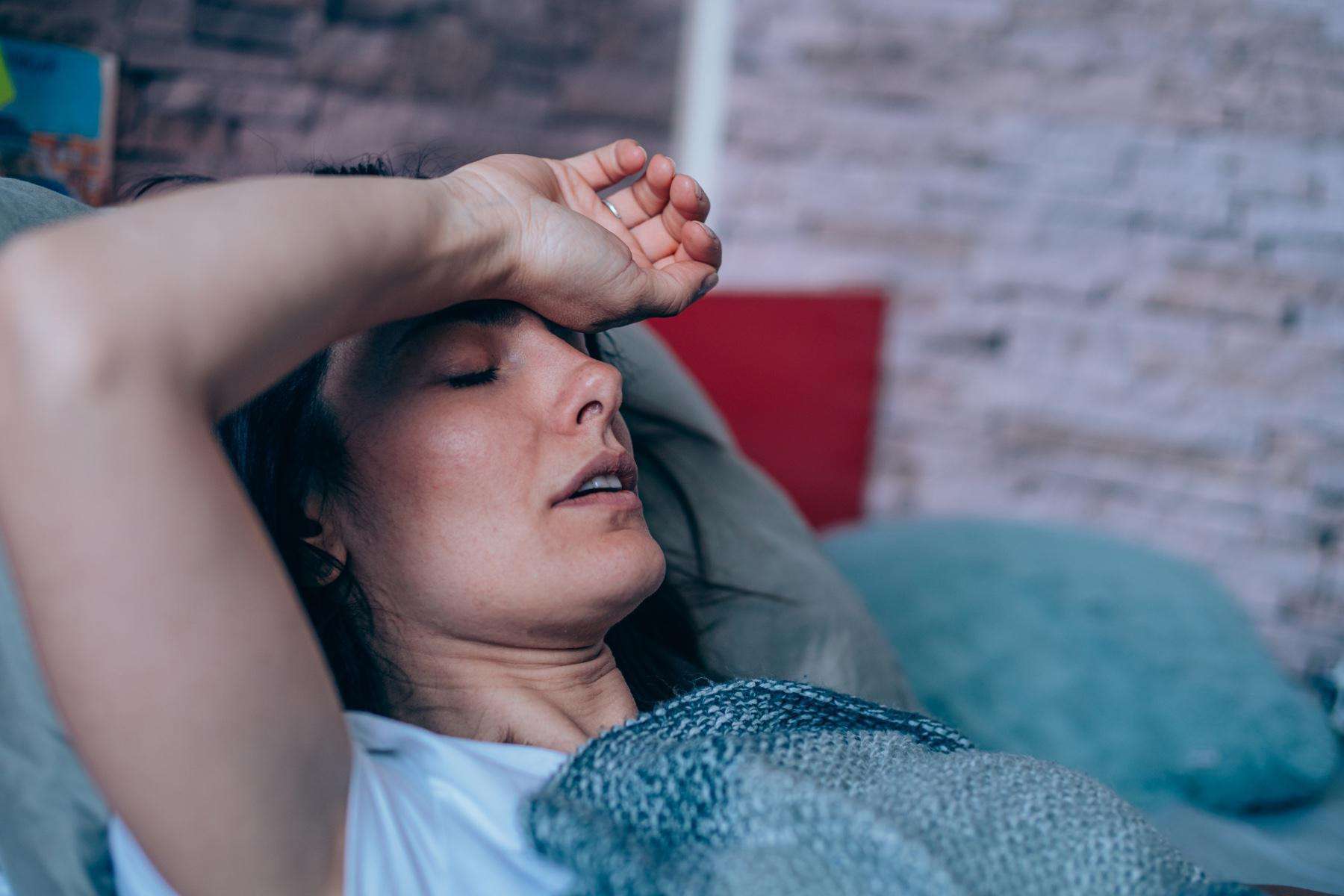 Woman having trouble sleeping close-up with arm on forehead.