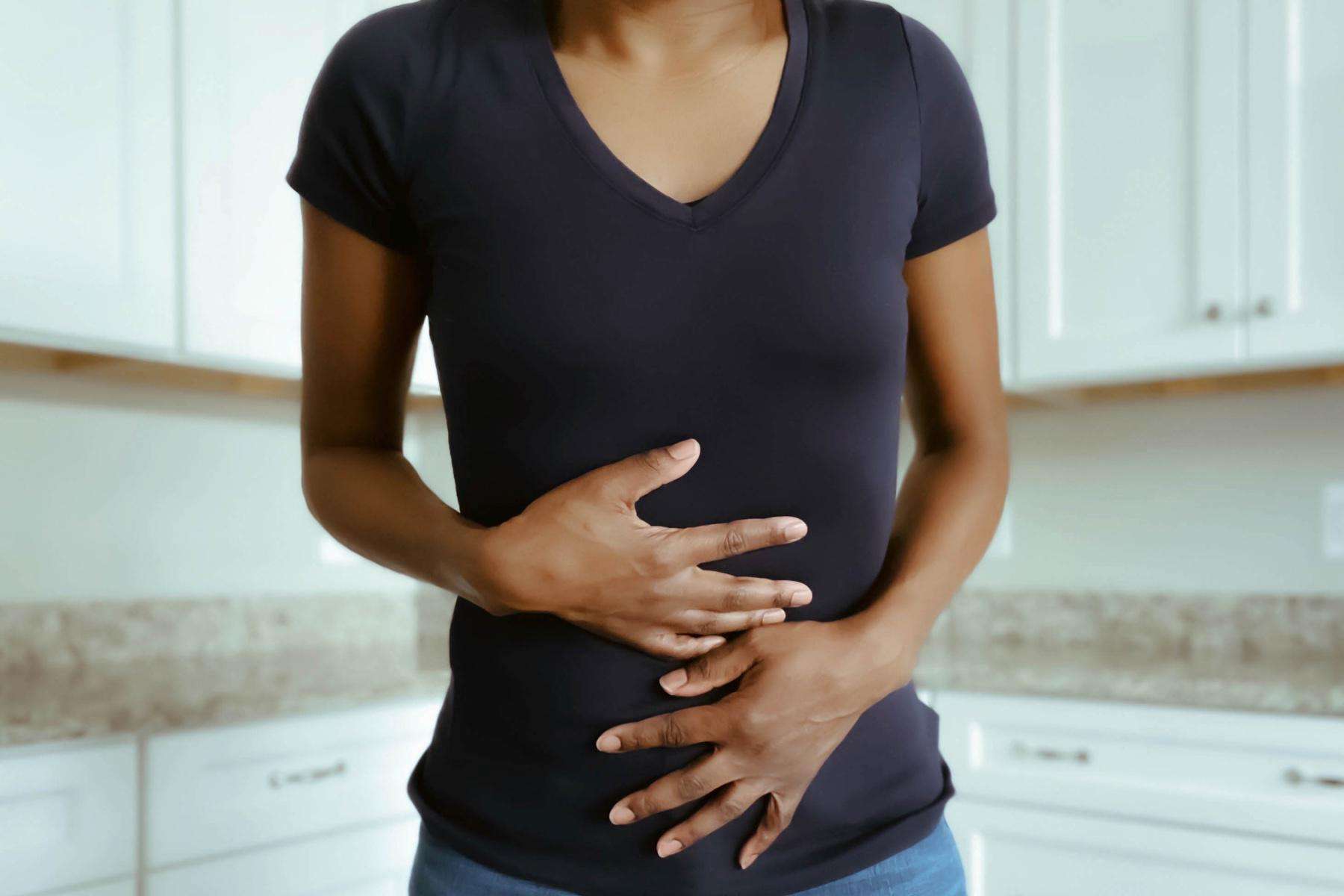 Woman with hands on stomach in pain.