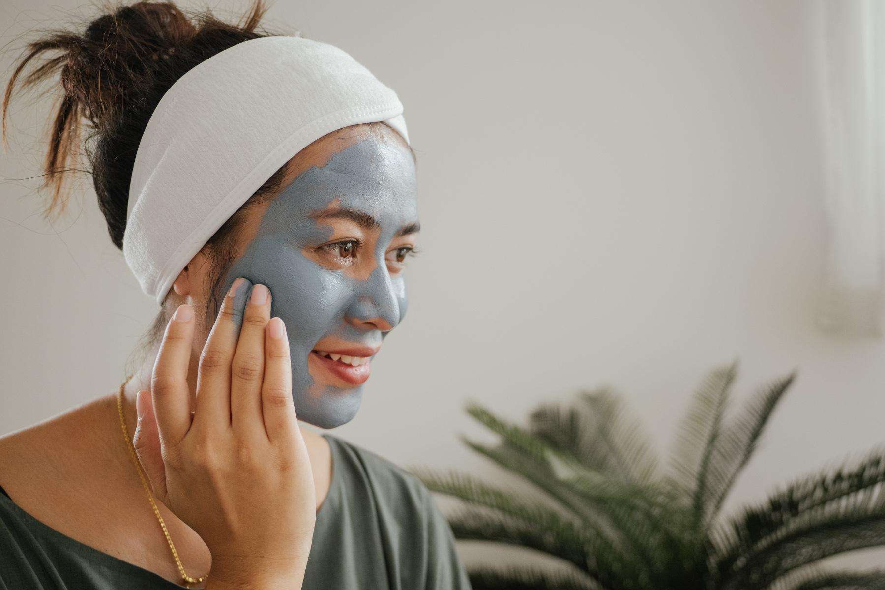 A young woman in her bathroom applying a facemask.