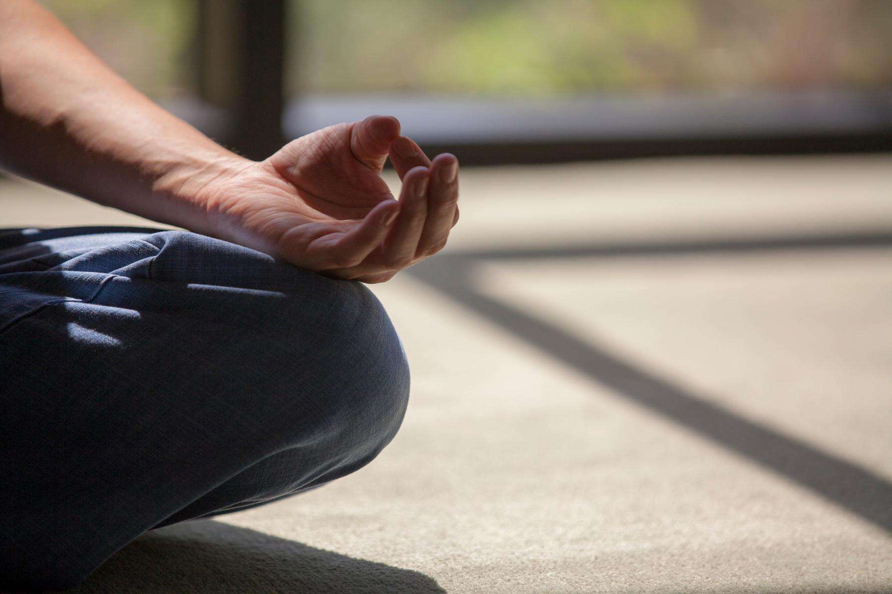Close-up of hand in meditation position on leg.