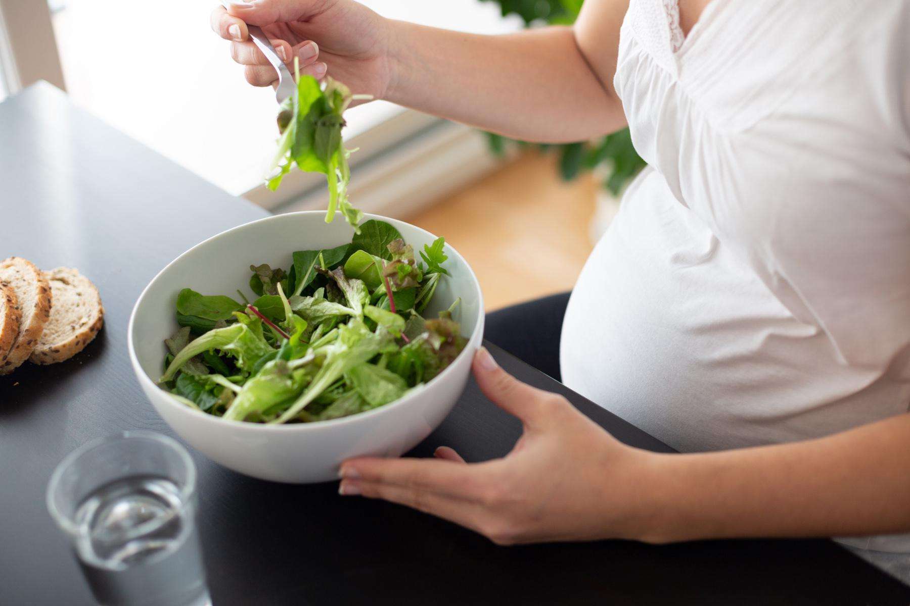 close-up of pregnant woman eating salad
