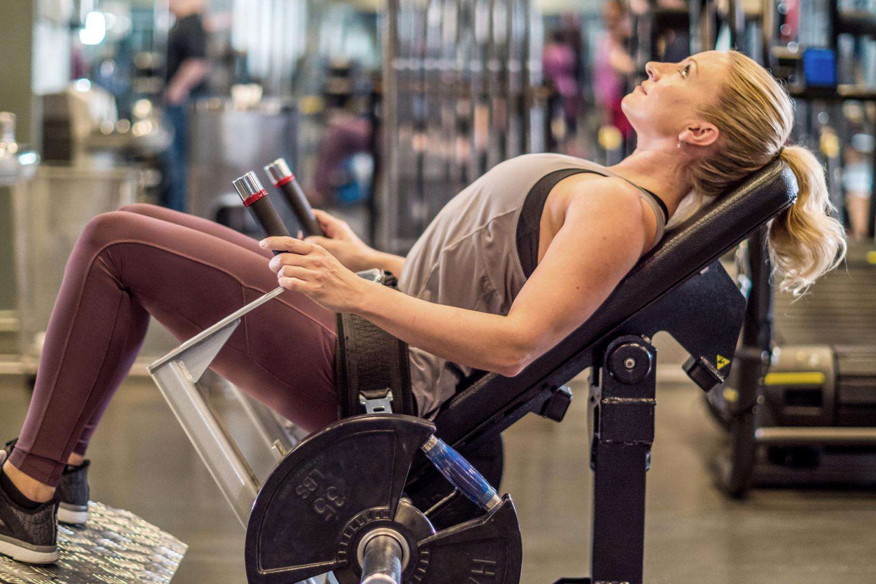 side view of woman as she uses a flute bridge machine in gym