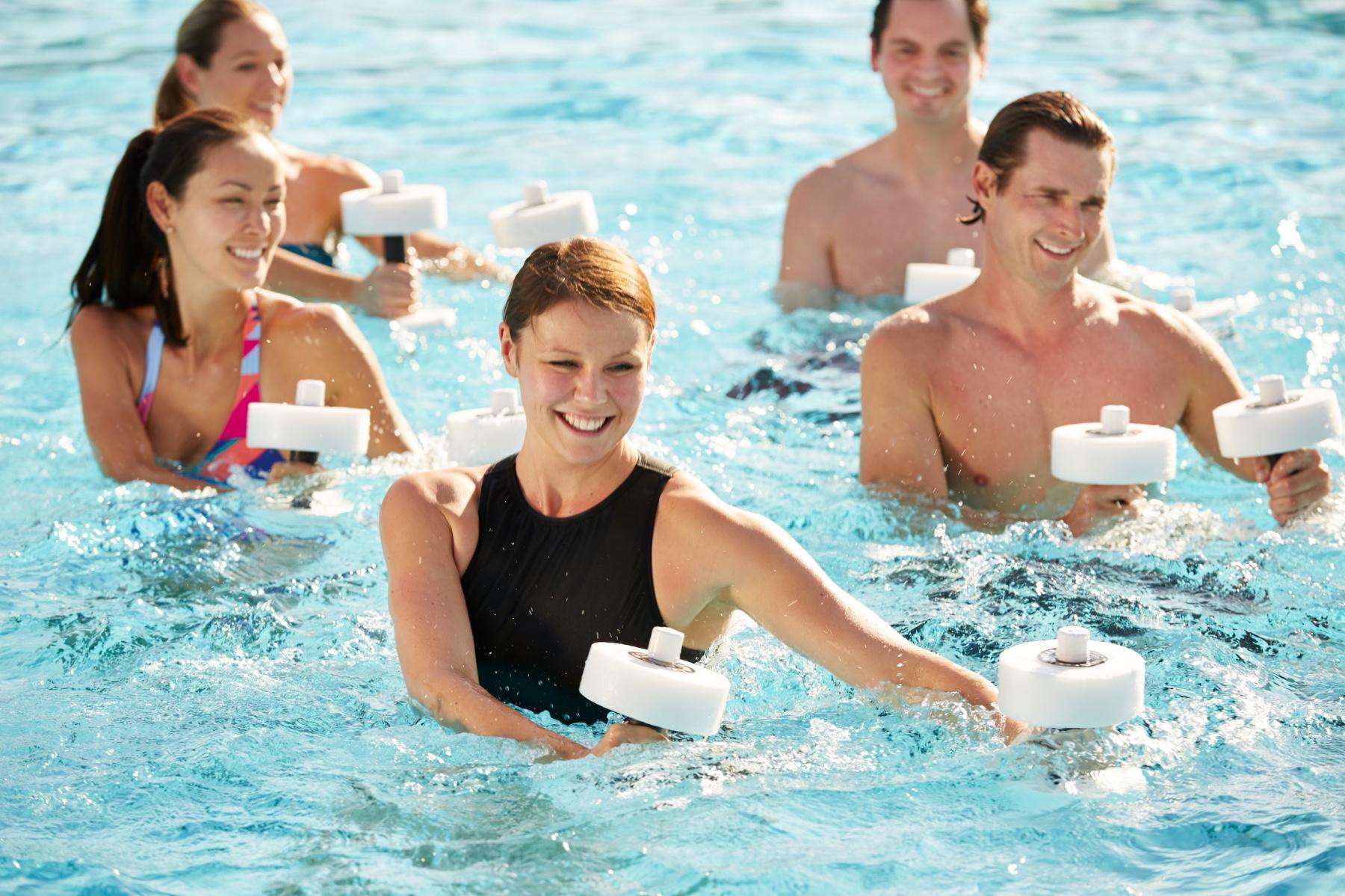 three women and two men in a pool using water aerobic weights