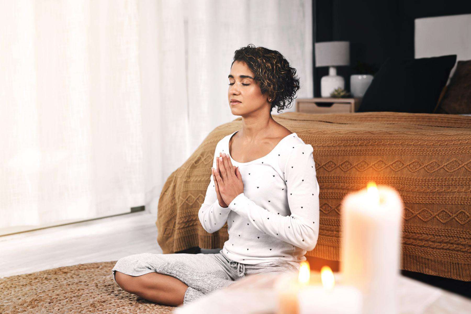 Woman meditating in her bedroom.