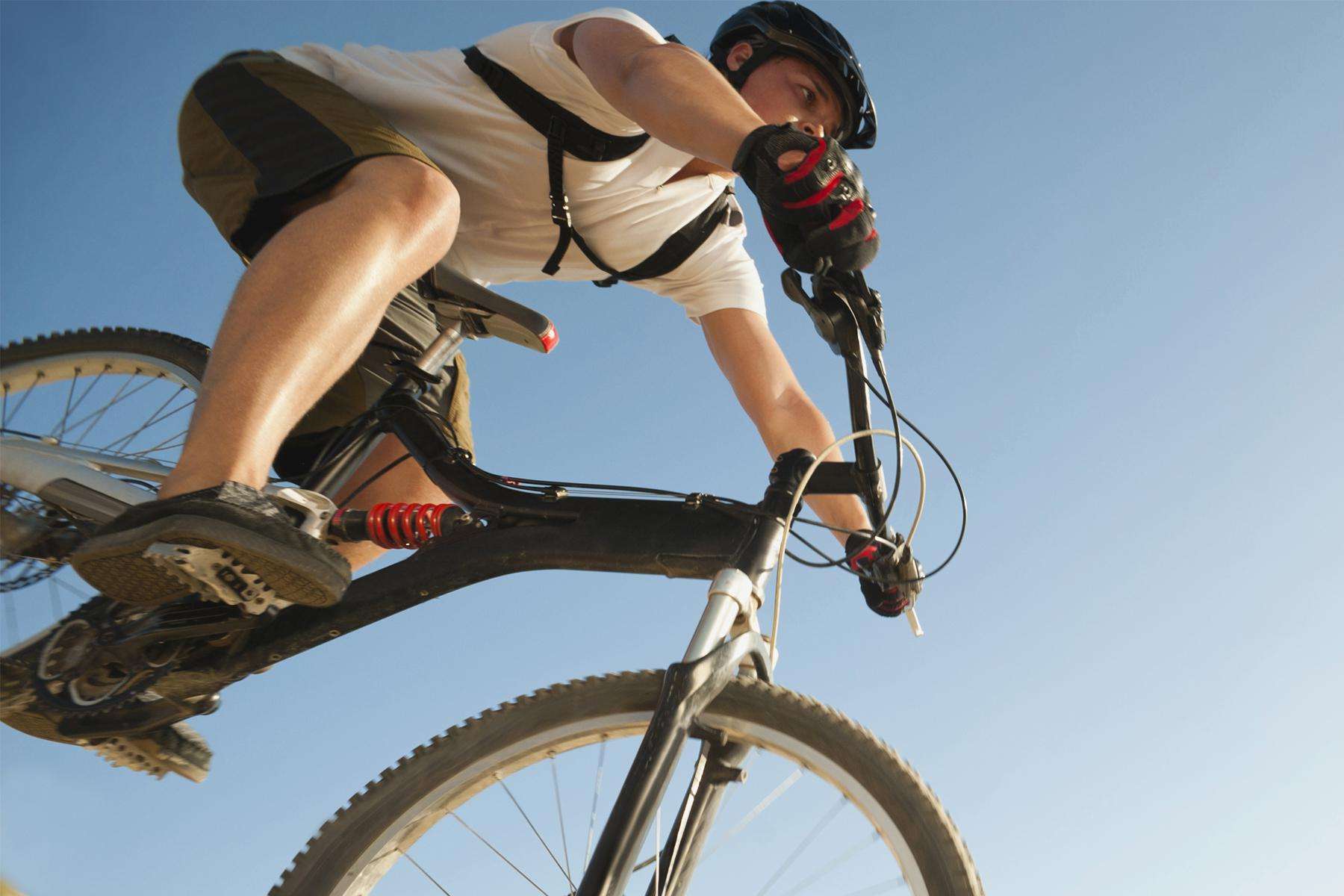 Close-up of cyclist riding bike outside against blue sky.