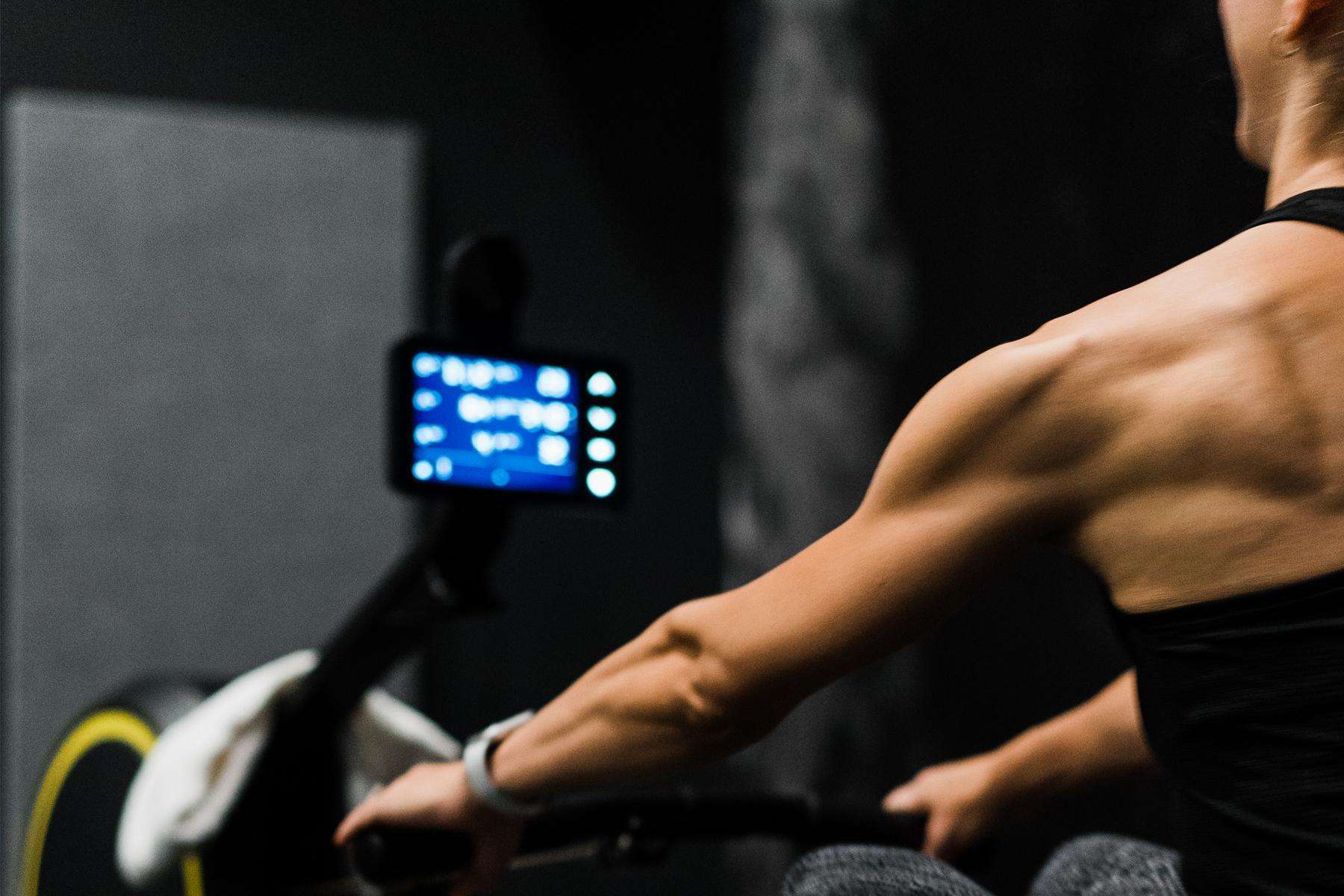 close-up of woman's back as she using rowing machine