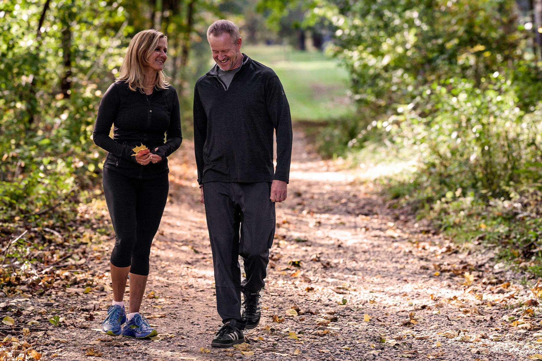 A couple walking together on a hiking trail through the woods.