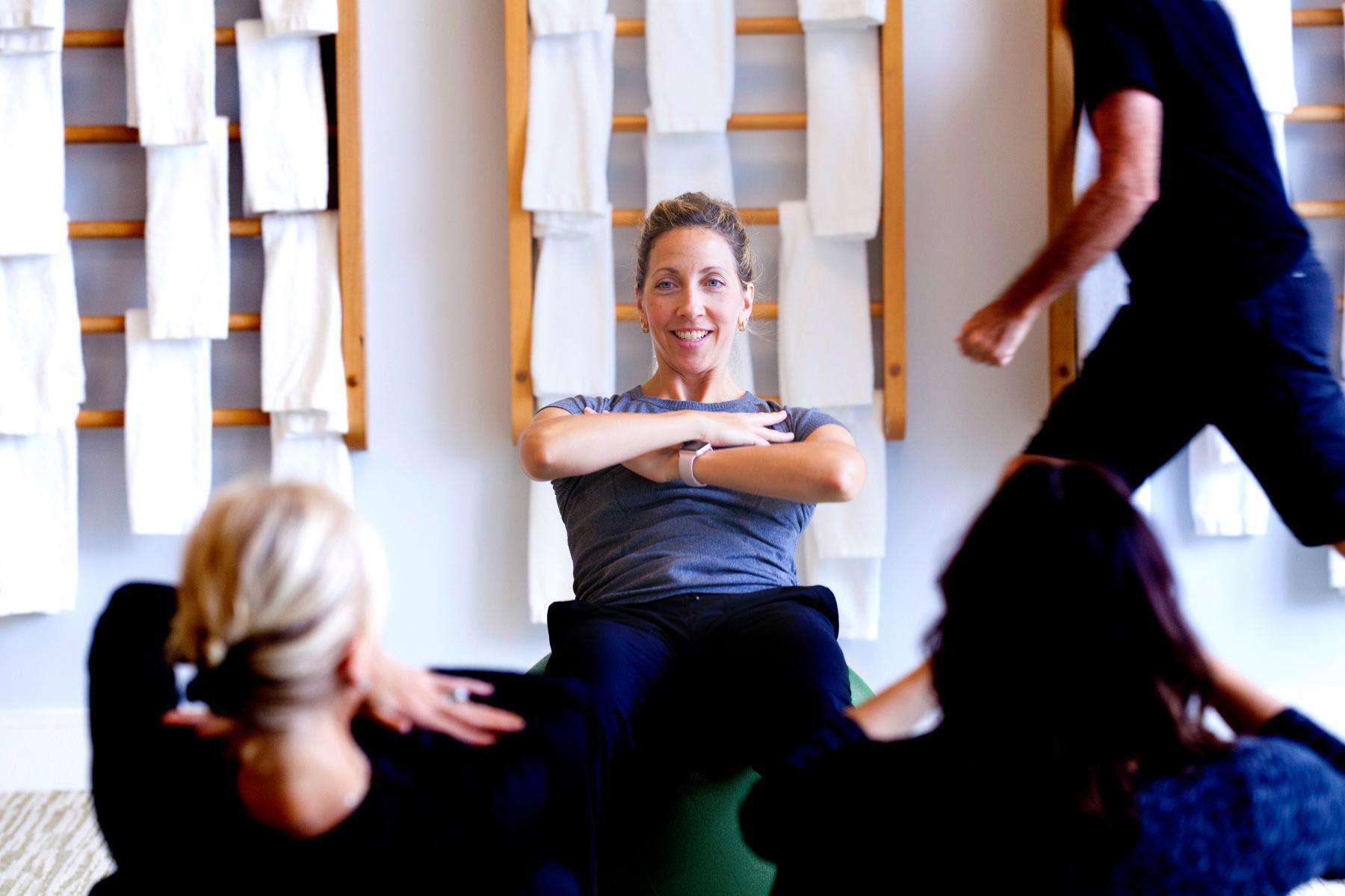 female fitness instructor showing class how to do crunches on workout ball