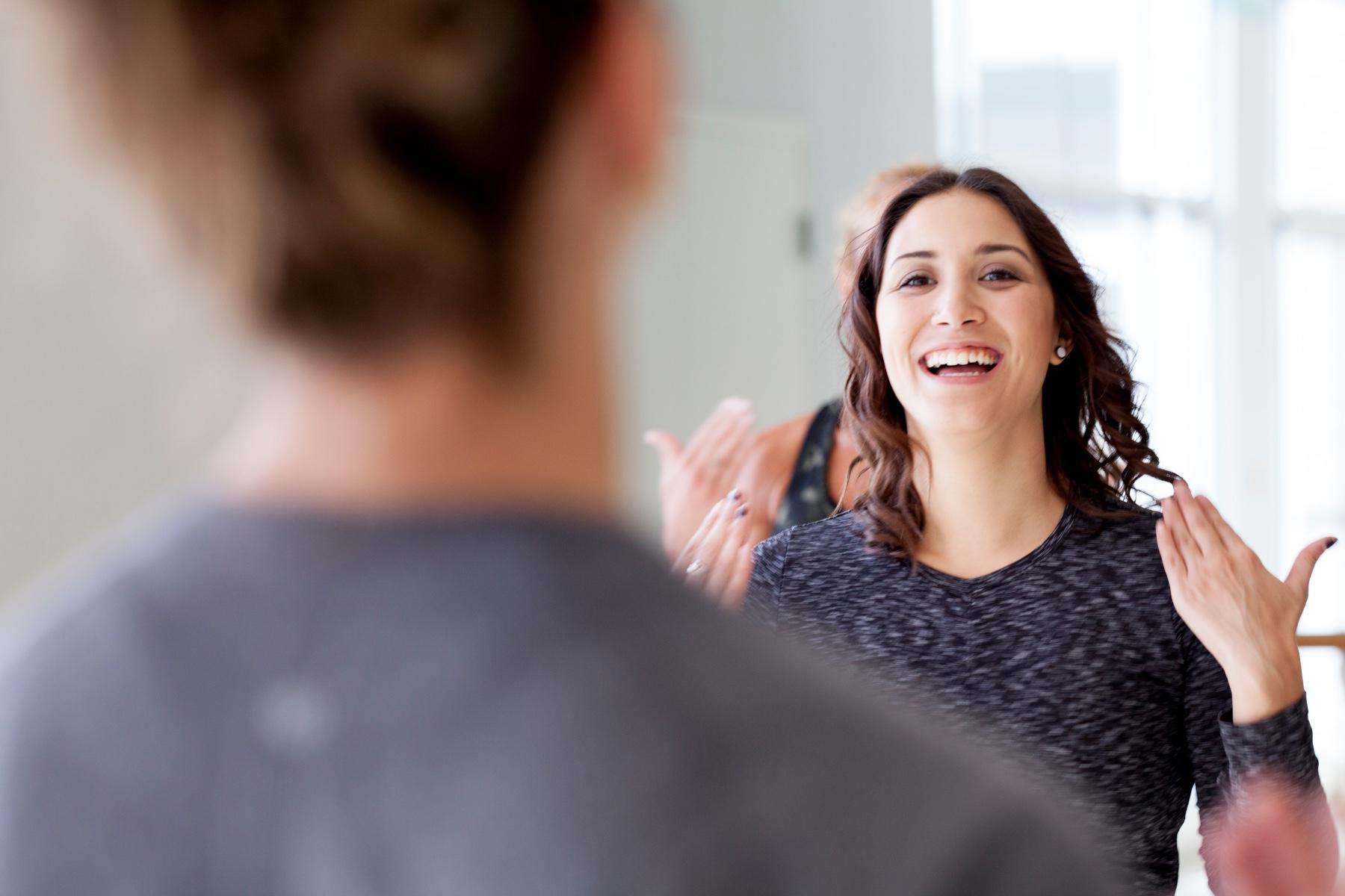 close-up of young woman's smiling face in a workout class with blurred people in foreground and background